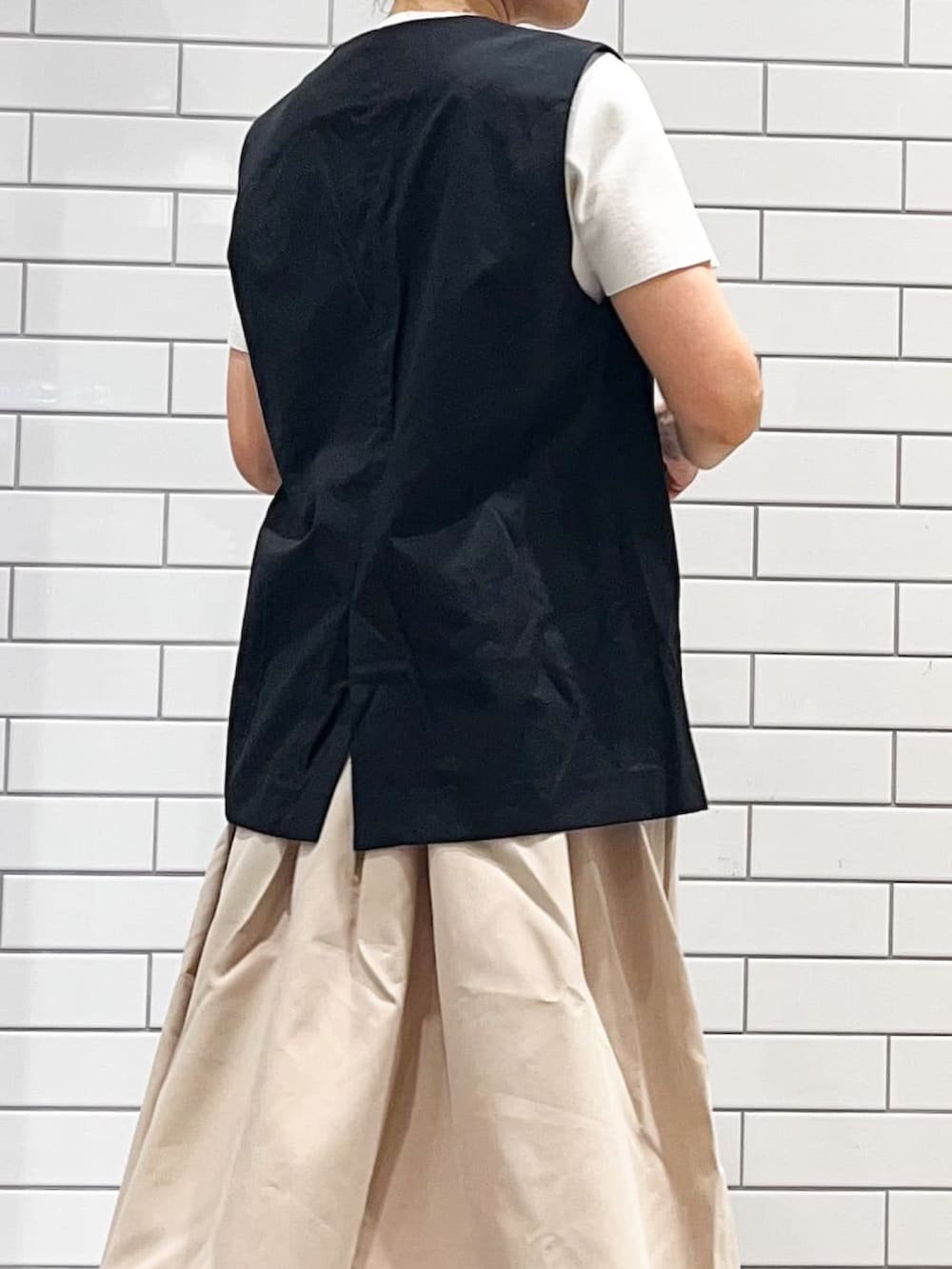 ブラック系のベスト、ベージュ系のワンピース、ブラック系のサンダルを着用したレディースの夏コーディネートの3枚目の写真