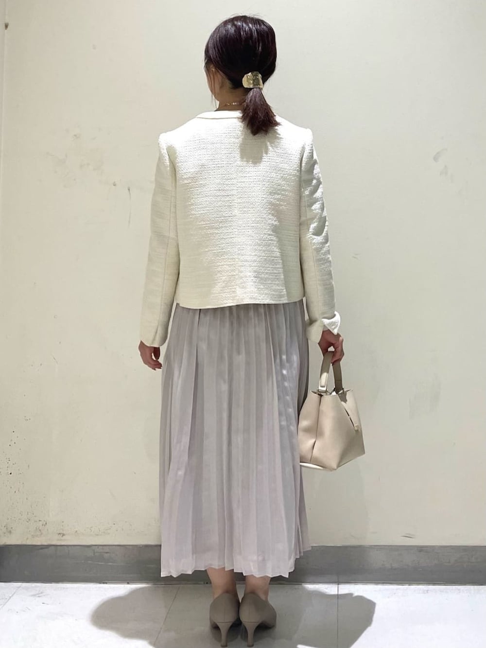 ホワイト系のノーカラージャケット、ベージュ系のワンピース、ベージュ系のショルダーバッグを着用したレディースの冬コーディネートの3枚目の写真