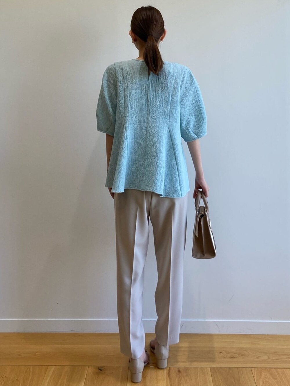 ブルー系のシャツ/ブラウス、ベージュ系のハンドバッグ、グレー系のその他パンツを着用したレディースの春コーディネートの4枚目の写真