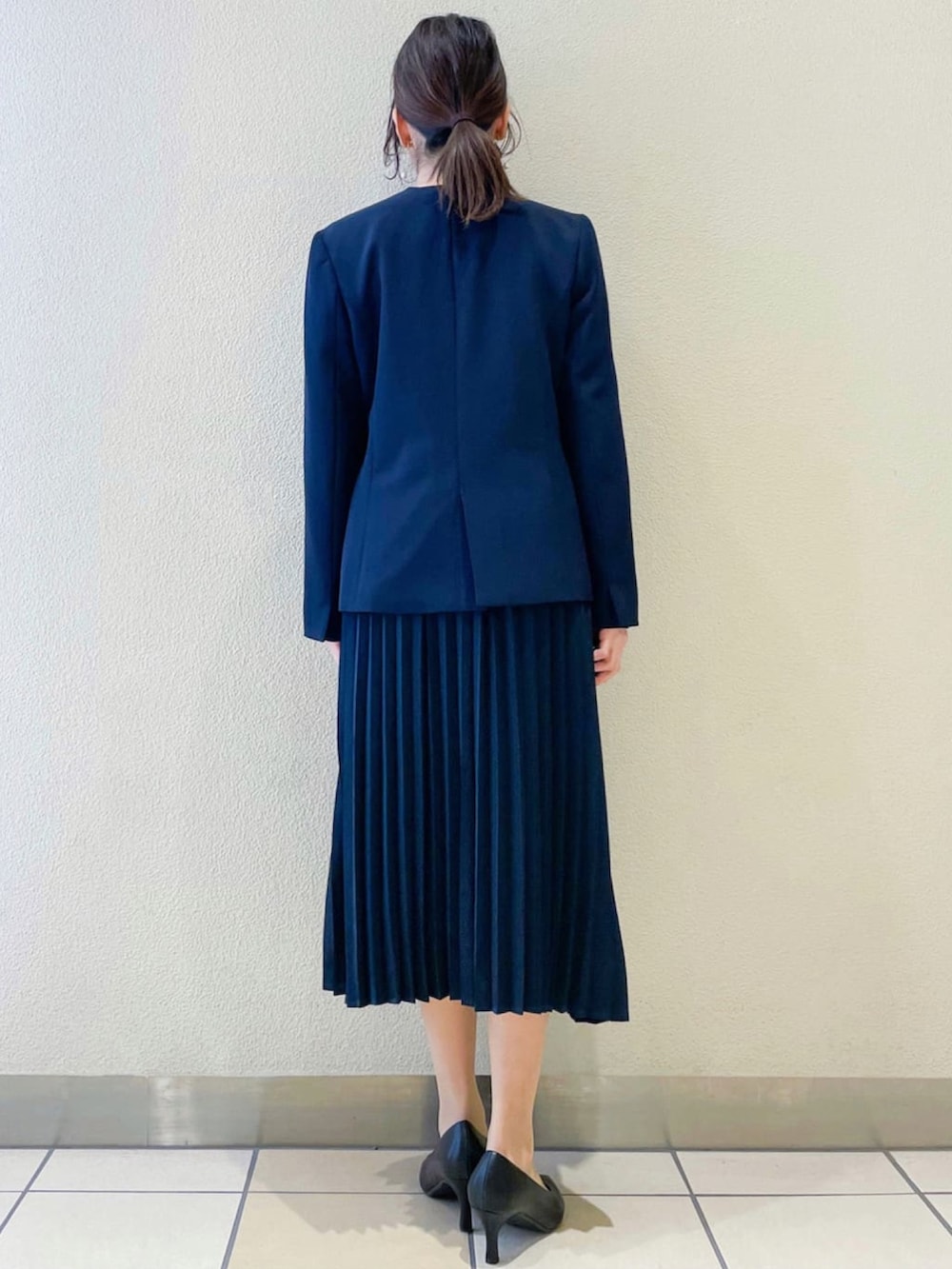 ブルー系のノーカラージャケット、ブルー系のワンピース、ベージュ系のトートバッグを着用したレディースの冬コーディネートの3枚目の写真