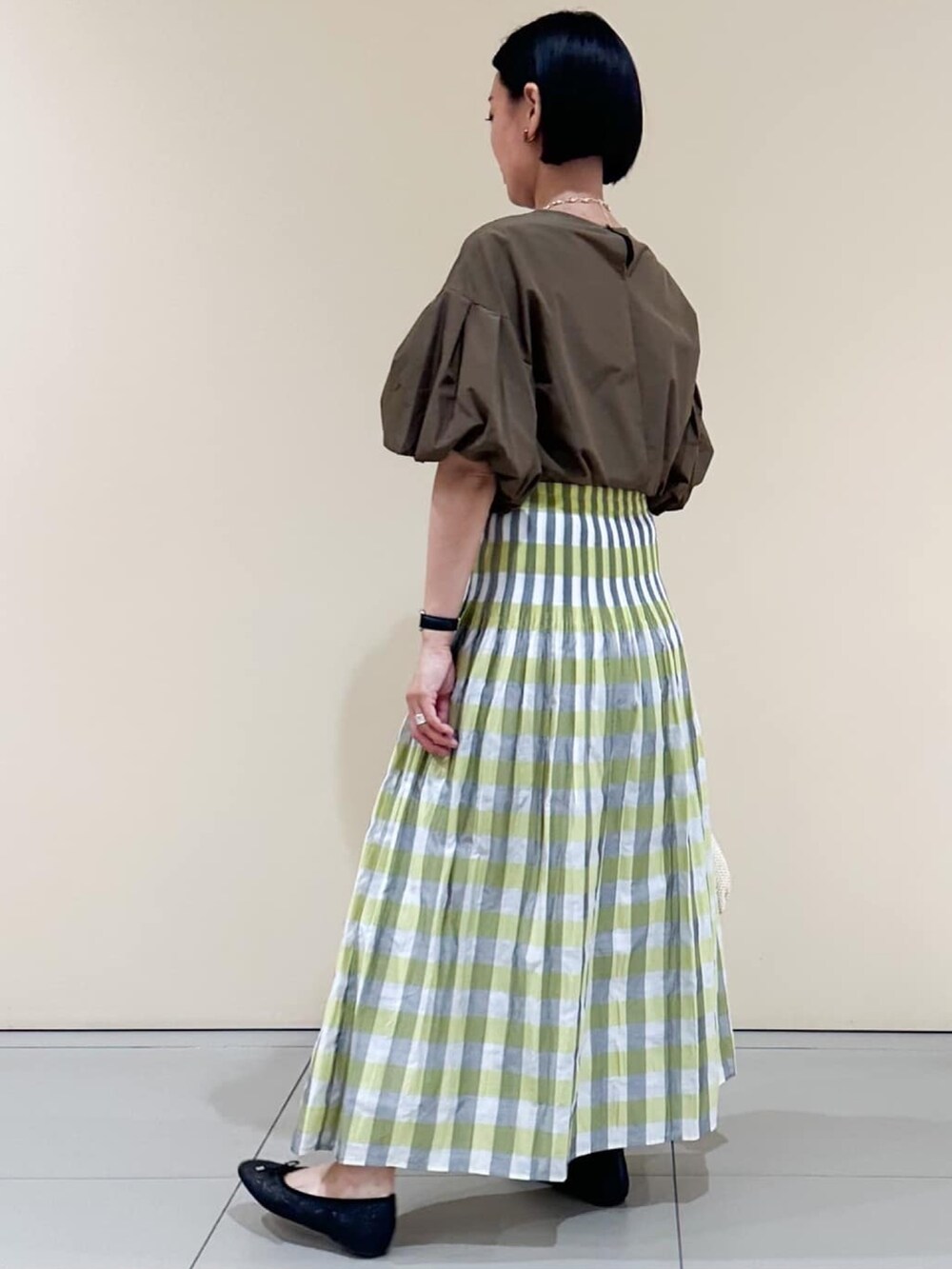 イエロー系のスカート、ブラック系のパンプス、ブラウン系のシャツ/ブラウスを着用したレディースの夏コーディネートの2枚目の写真