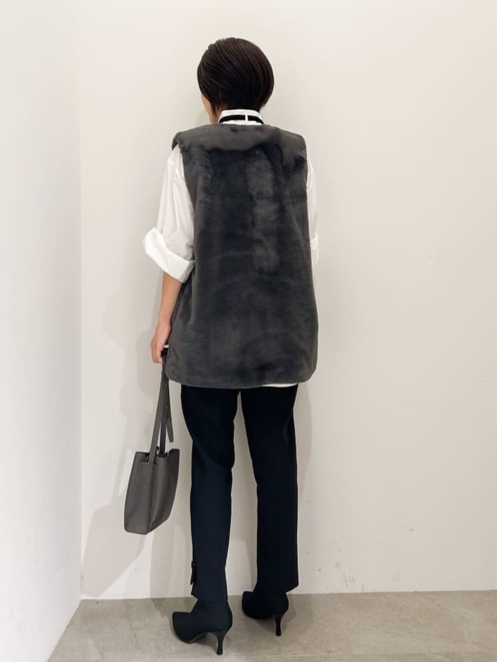 グレー系のベスト、ホワイト系のシャツ/ブラウス、ブラック系のその他パンツを着用したレディースの秋コーディネートの3枚目の写真