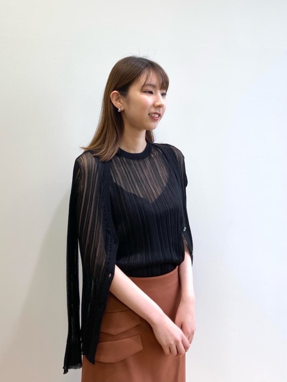 ブラウン系のスカート、シルバー系のサンダル、ブラック系のニット/セーターを着用したレディースの春コーディネートの5枚目の写真