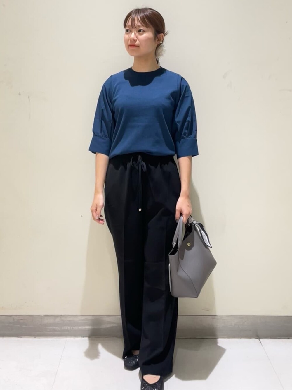 ブルー系のニット/セーター、ブラック系のその他パンツ、グレー系のトートバッグを着用したレディースの夏コーディネートの2枚目の写真