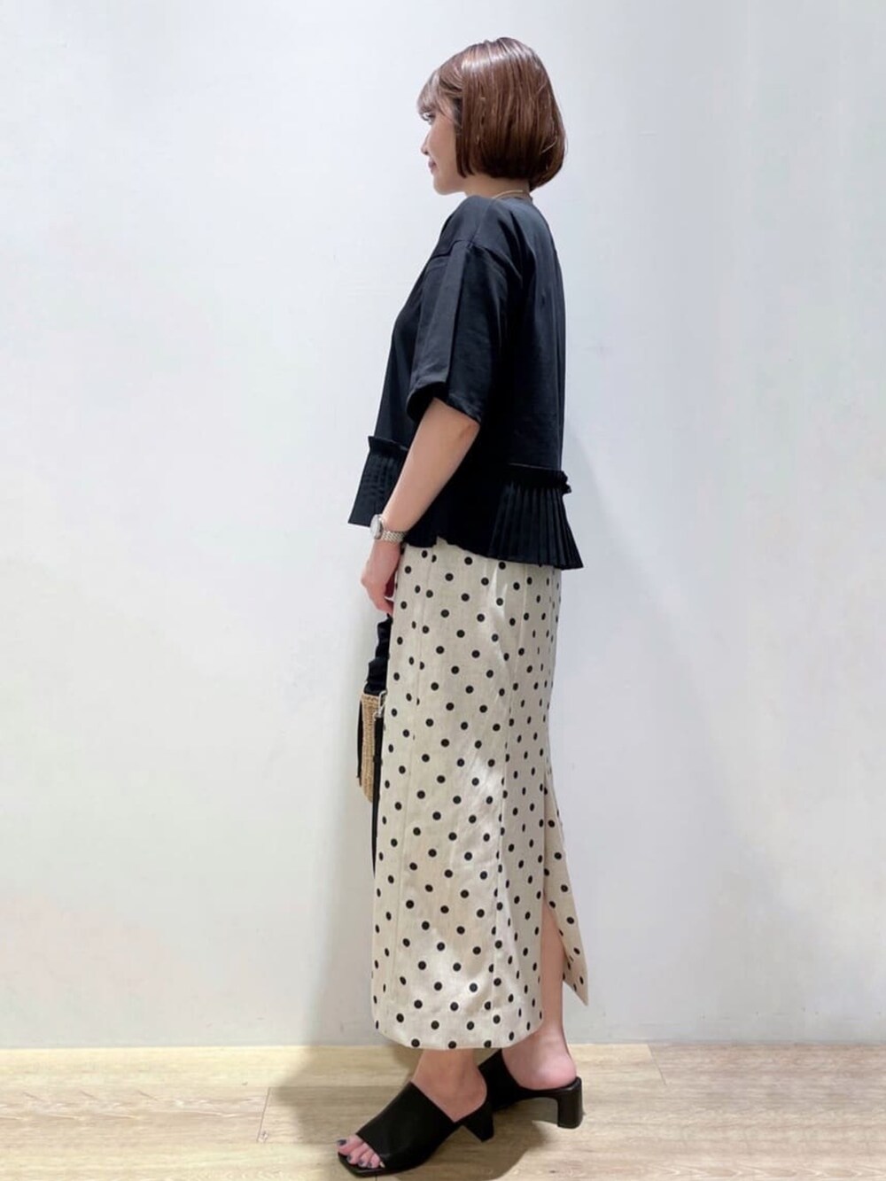 ベージュ系のスカート、ブラック系のTシャツ/カットソー、ブラック系のサンダルを着用したレディースの夏コーディネートの2枚目の写真