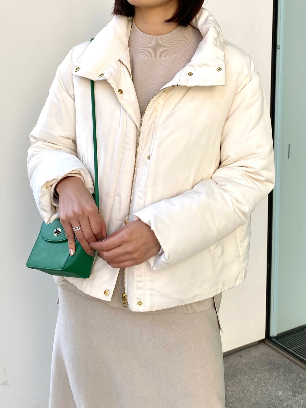 ホワイト系のブルゾン、ベージュ系のニット/セーター、グリーン系のショルダーバッグを着用したレディースの冬コーディネートの5枚目の写真