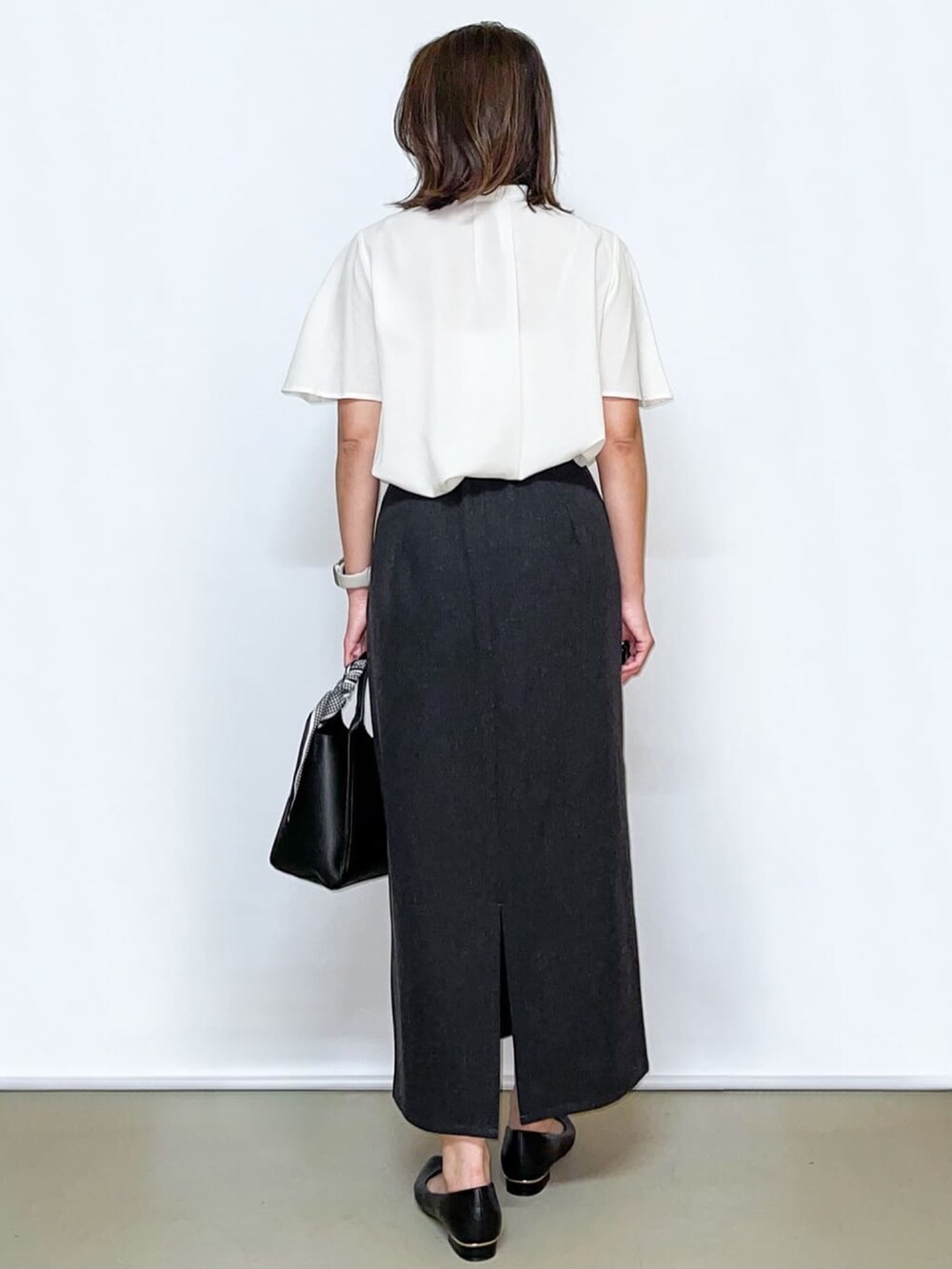 ホワイト系のシャツ/ブラウス、グレー系のスカート、ブラック系のトートバッグを着用したレディースの夏コーディネートの6枚目の写真