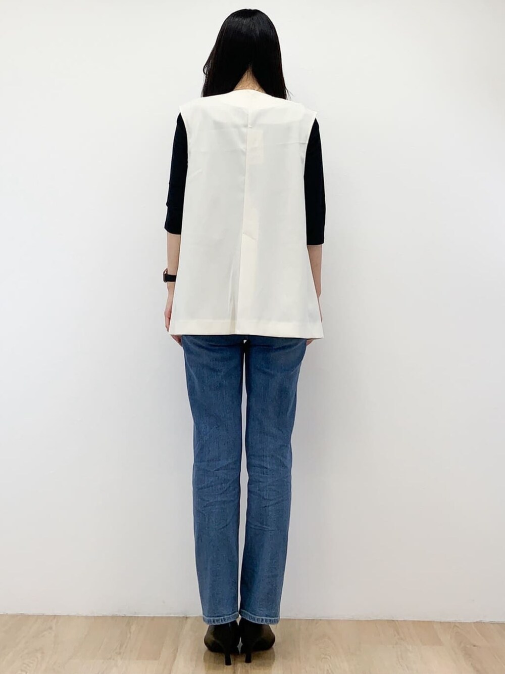 ホワイト系のベスト、ブラック系のTシャツ/カットソー、ブルー系のデニムパンツを着用したレディースの秋コーディネートの3枚目の写真
