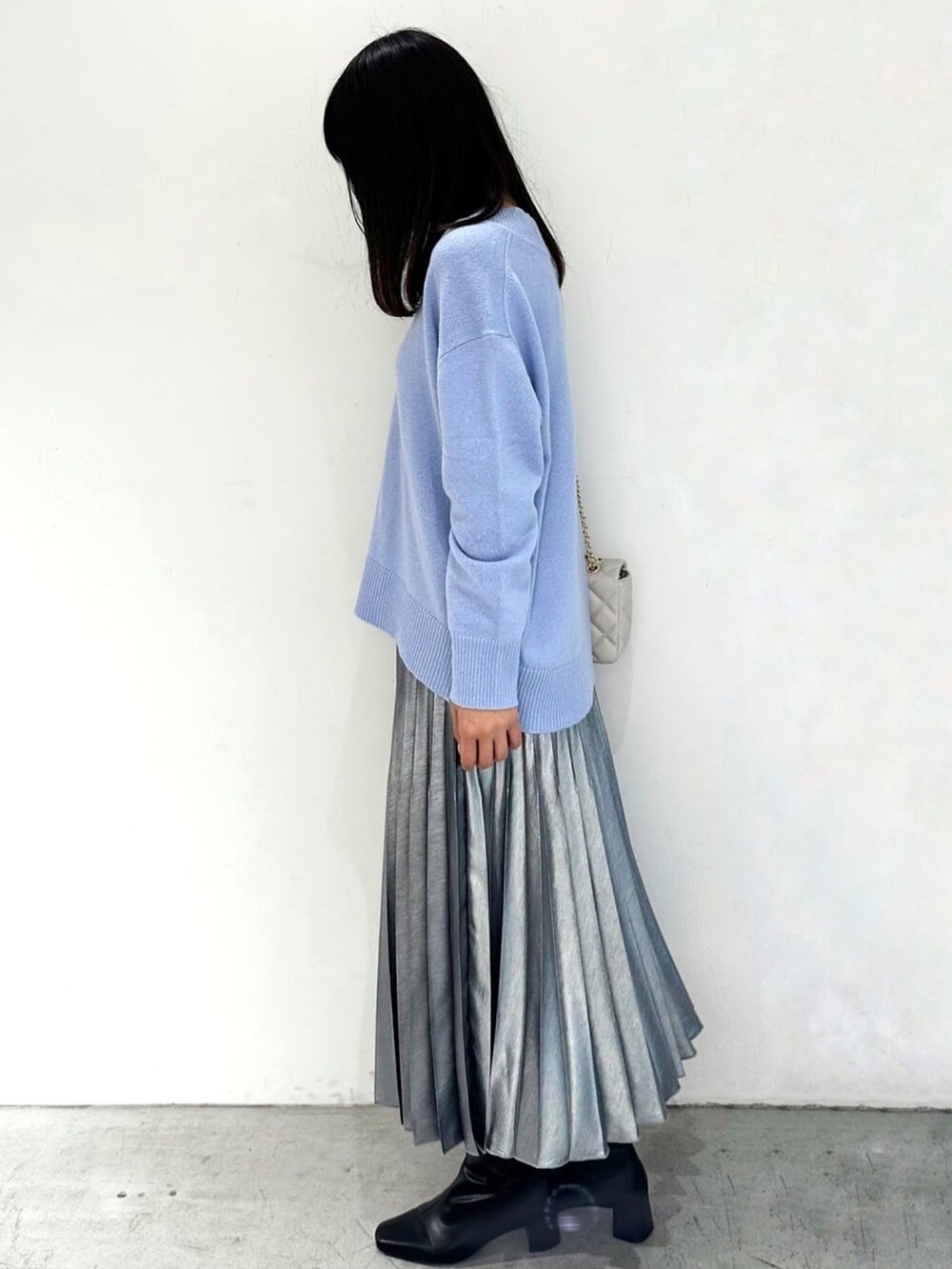 ブルー系のニット/セーター、ブラック系のスカート、ブラック系のブーツを着用したレディースの秋コーディネートの2枚目の写真