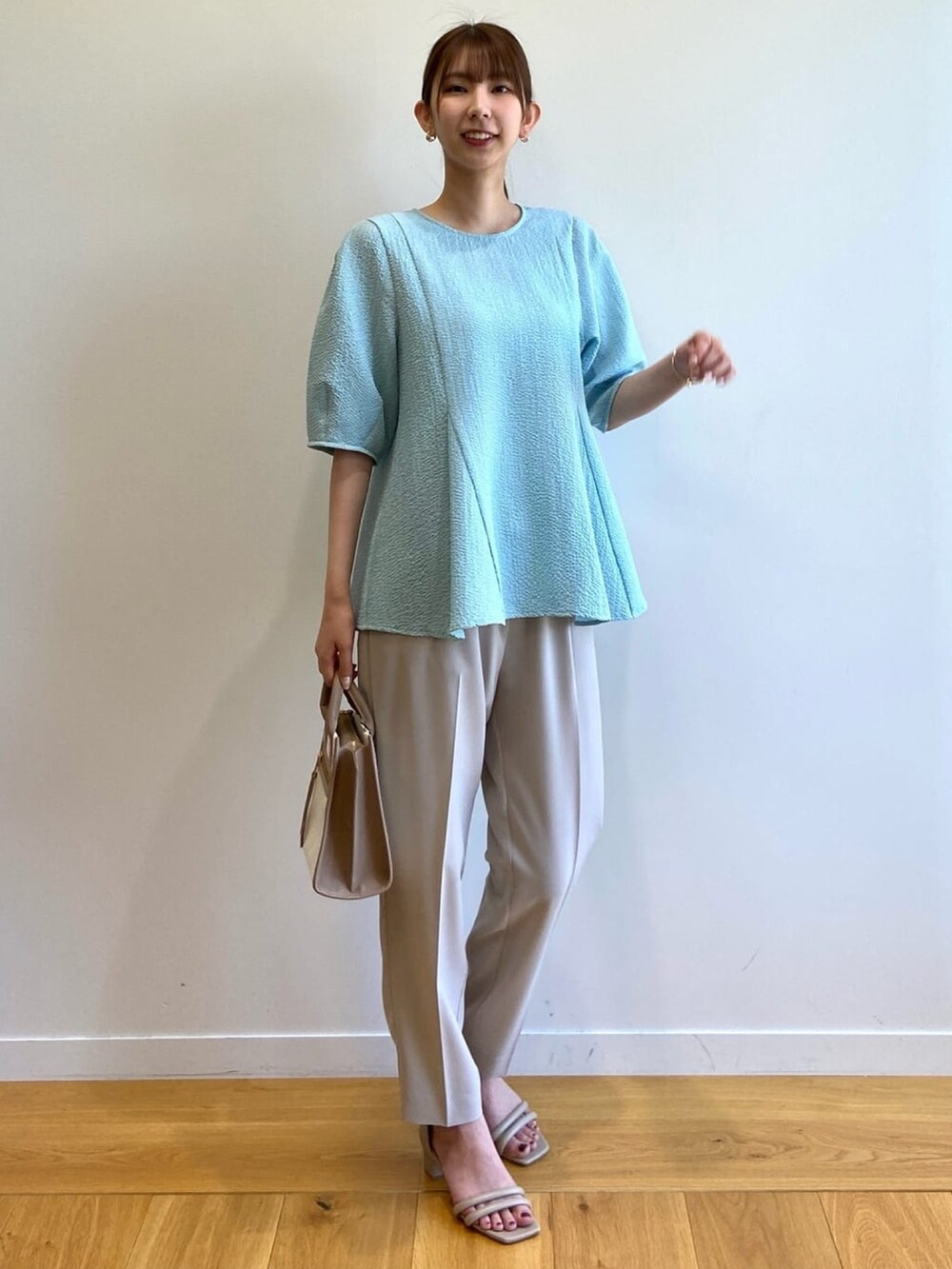 ブルー系のシャツ/ブラウス、ベージュ系のハンドバッグ、グレー系のその他パンツを着用したレディースの春コーディネートの2枚目の写真