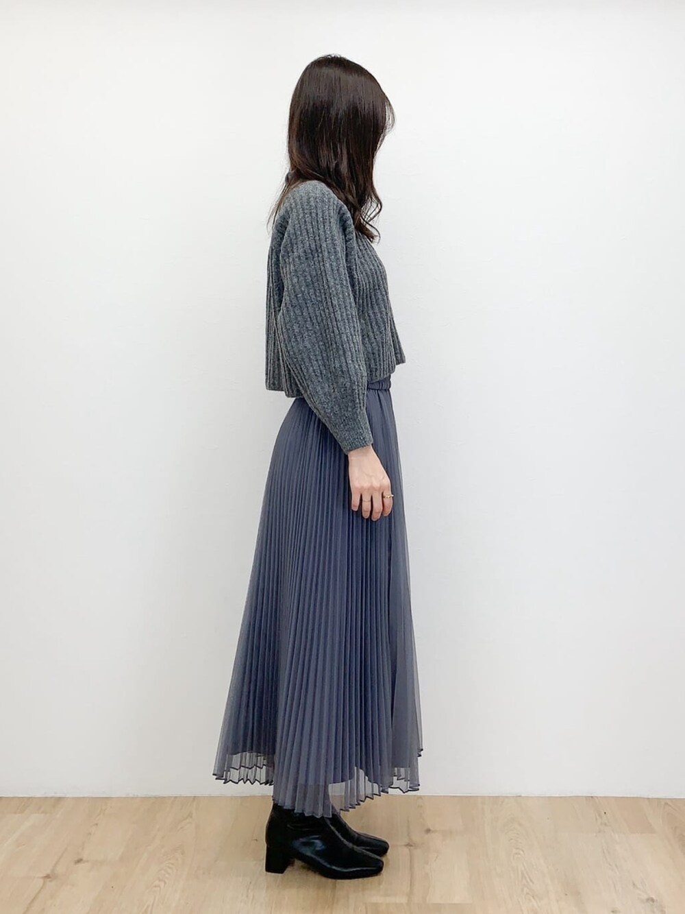 グレー系のニット/セーター、ブラック系のブーツ、グレー系のスカートを着用したレディースの冬コーディネートの2枚目の写真