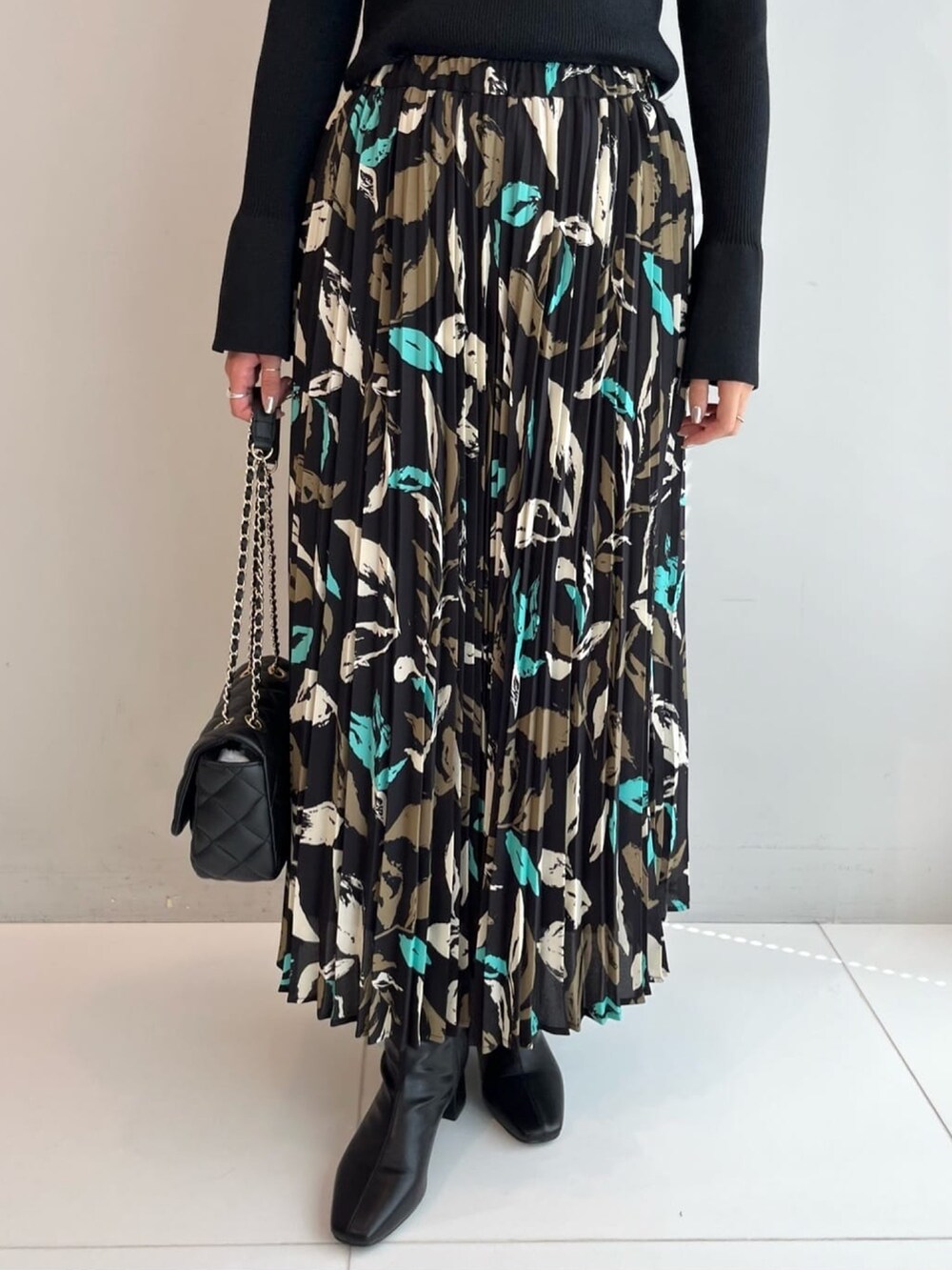 ブラック系のニット/セーター、ブラック系のスカート、ブラック系のショルダーバッグを着用したレディースの秋コーディネートの4枚目の写真