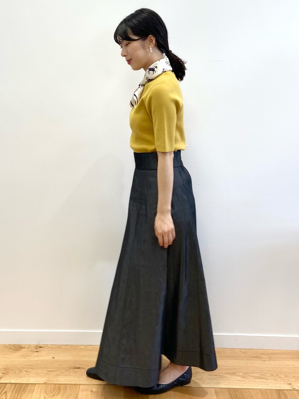 イエロー系のニット/セーター、その他のスカート、ブラック系のショルダーバッグを着用したレディースの夏コーディネートの3枚目の写真