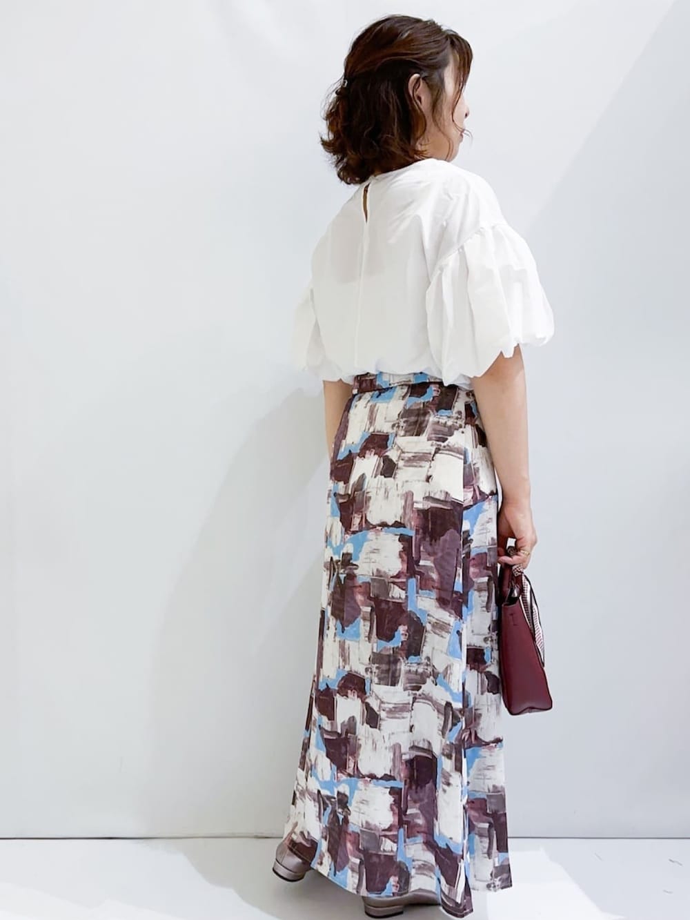 ホワイト系のシャツ/ブラウス、レッド系のスカート、レッド系のショルダーバッグを着用したレディースの夏コーディネートの6枚目の写真