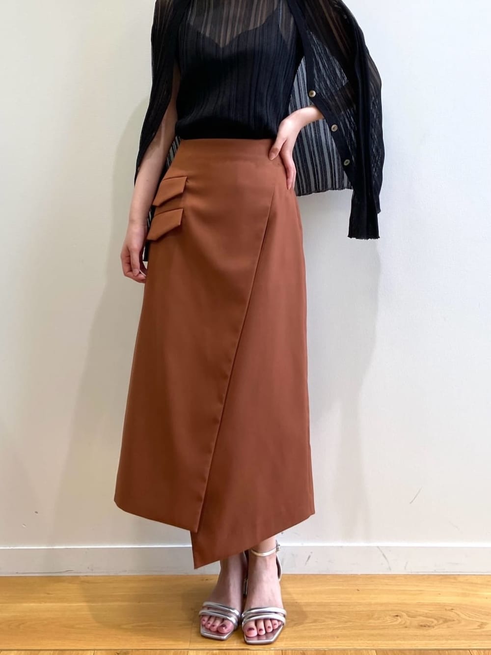 ブラウン系のスカート、シルバー系のサンダル、ブラック系のニット/セーターを着用したレディースの春コーディネートの6枚目の写真