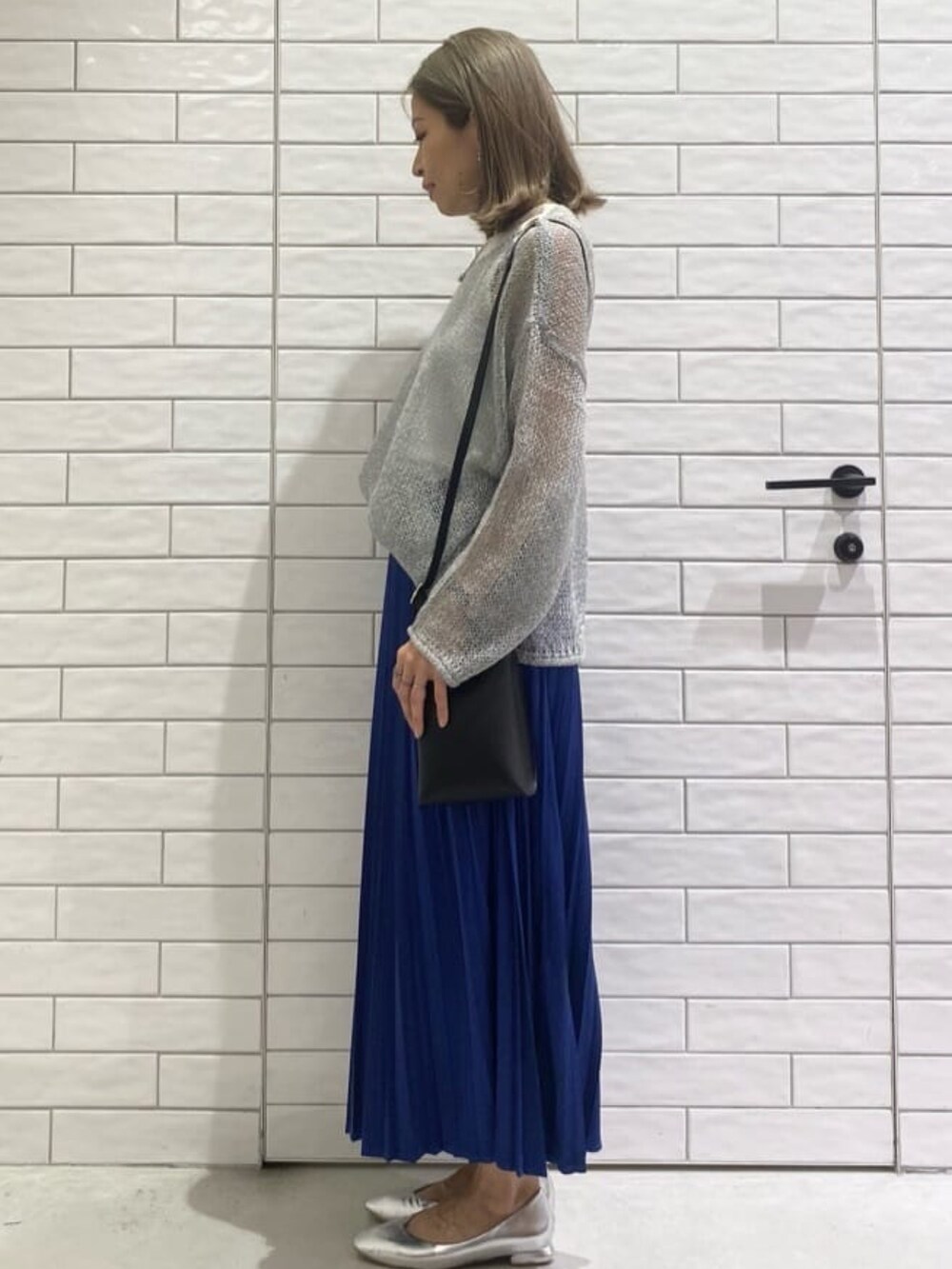 グレー系のニット/セーター、ホワイト系のタンクトップ、ブラック系のショルダーバッグを着用したレディースの秋コーディネートの2枚目の写真