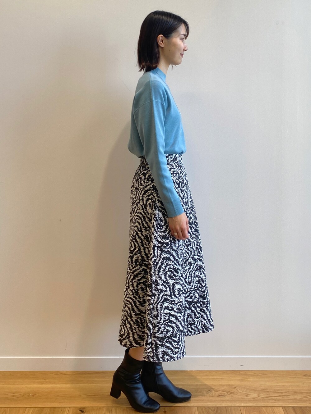 ブルー系のニット/セーター、ブラック系のスカート、ブラック系のブーツを着用したレディースの冬コーディネートの2枚目の写真