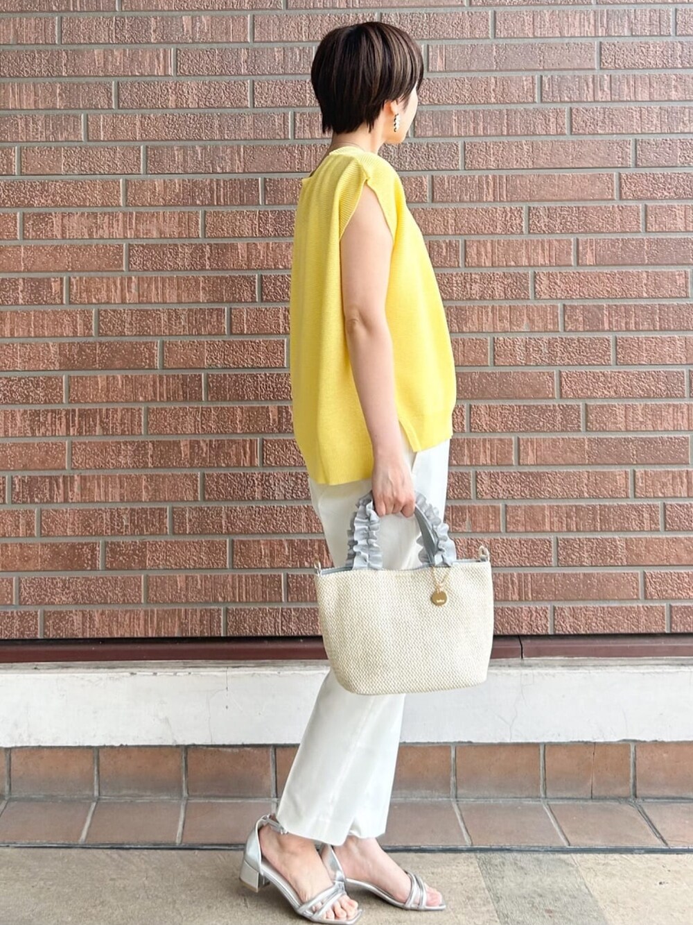 ホワイト系のその他パンツ、グレー系のトートバッグ、シルバー系のサンダルを着用したレディースの春コーディネートの3枚目の写真