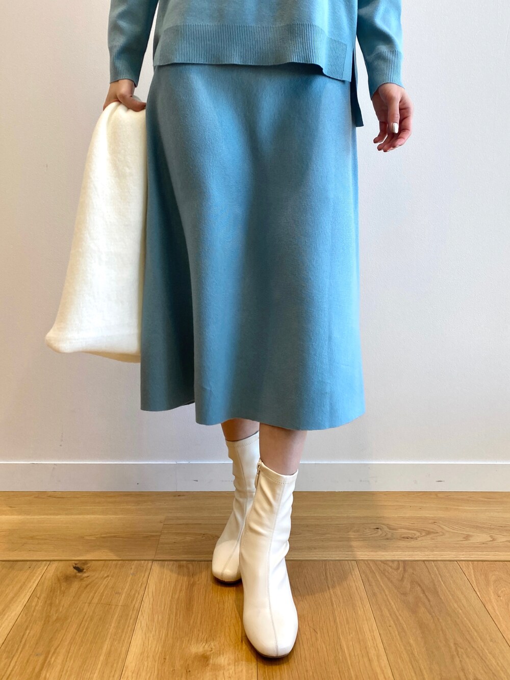 ブルー系のニット/セーター、ブルー系のスカート、ホワイト系のブーツを着用したレディースの冬コーディネートの5枚目の写真
