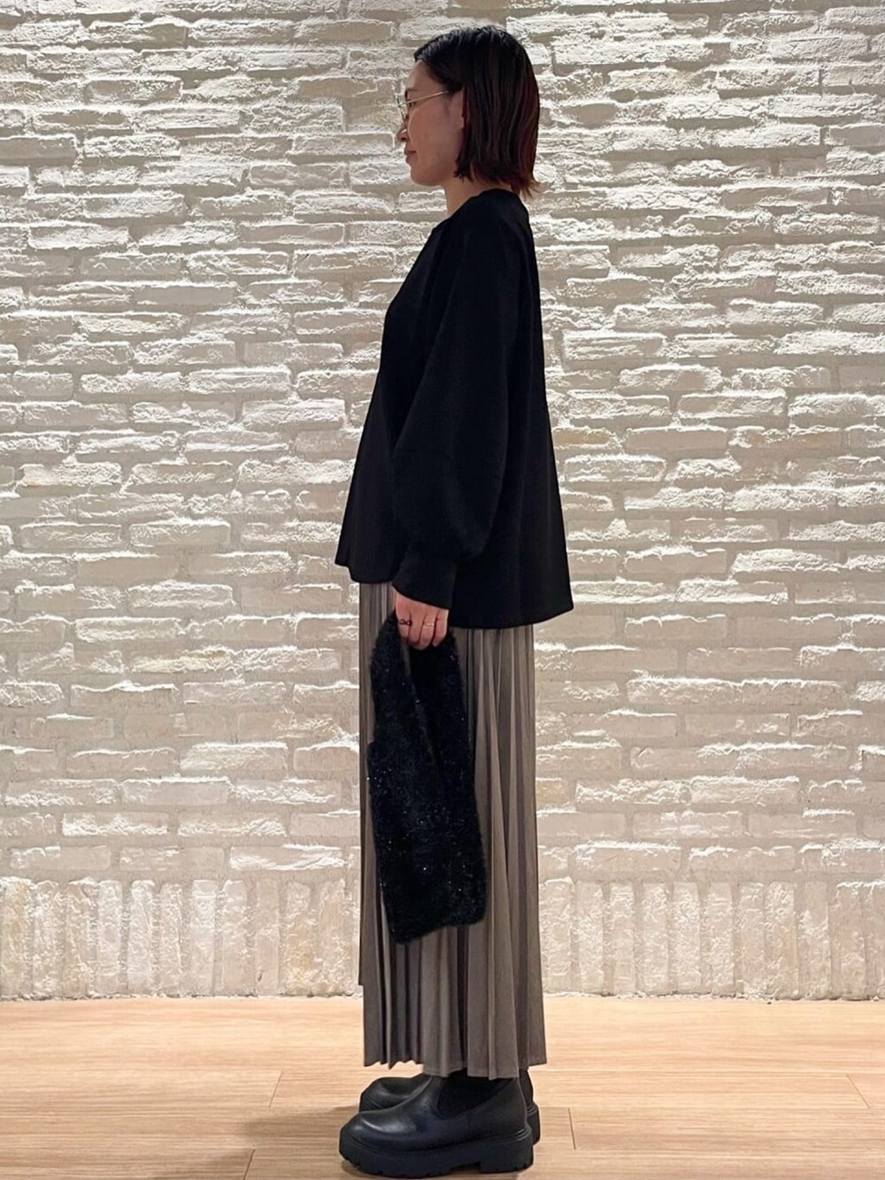 ブラック系のTシャツ/カットソー、グレー系のスカート、ブラック系のハンドバッグを着用したレディースの秋コーディネートの2枚目の写真