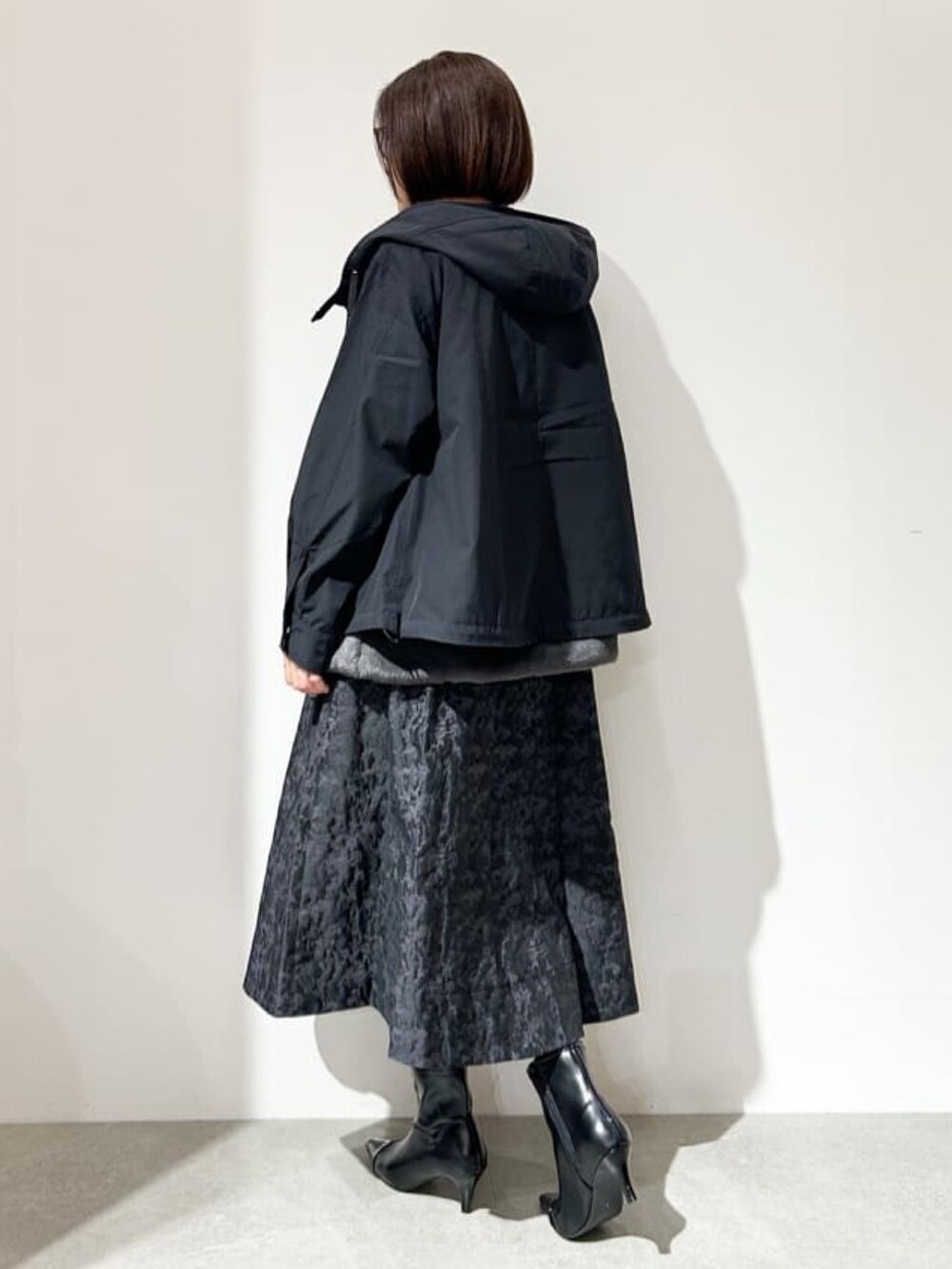 ブラック系のブルゾン、グリーン系のニット/セーター、ブラック系のスカートを着用したレディースの秋コーディネートの3枚目の写真