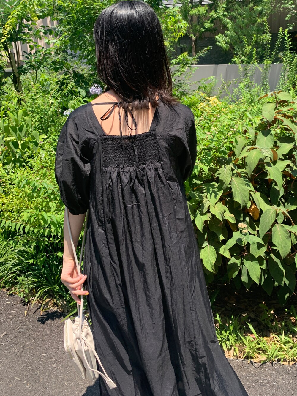 ブラック系のワンピース、ホワイト系のショルダーバッグ、ゴールド系のサンダルを着用したレディースの夏コーディネートの3枚目の写真