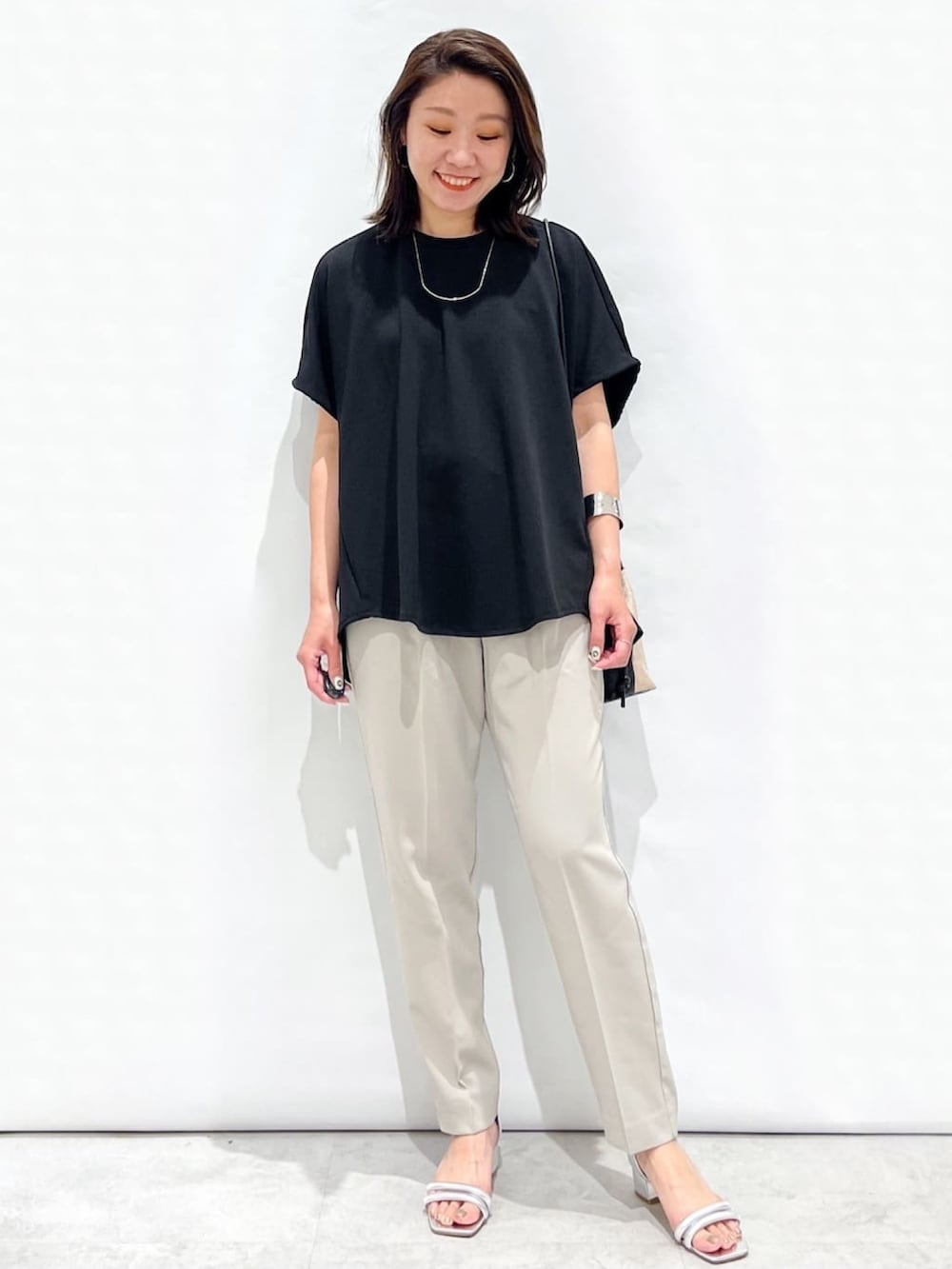 ブラック系のTシャツ/カットソー、グレー系のその他パンツ、シルバー系のサンダルを着用したレディースの春コーディネートの2枚目の写真