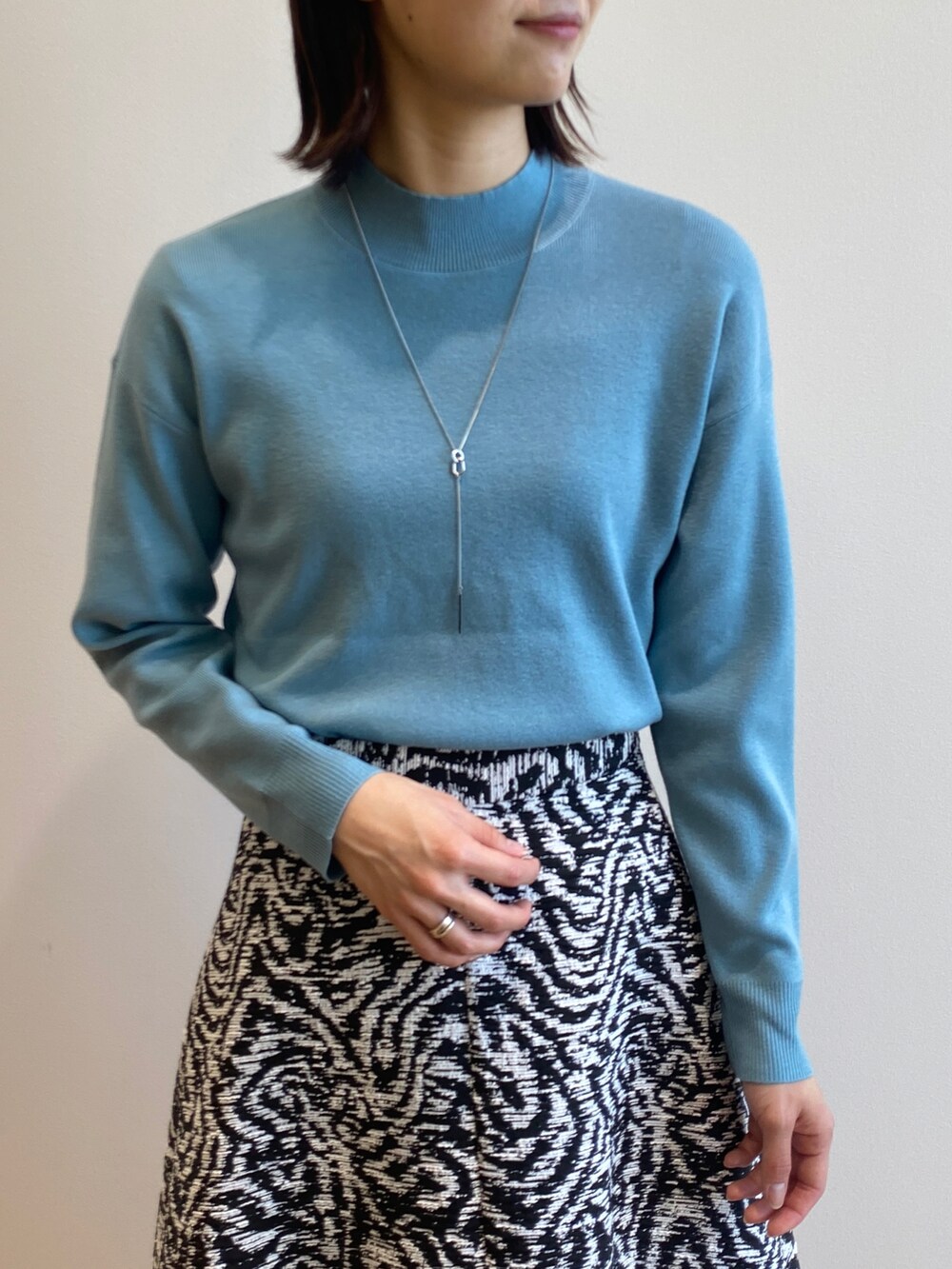 ブルー系のニット/セーター、ブラック系のスカート、ブラック系のブーツを着用したレディースの冬コーディネートの3枚目の写真