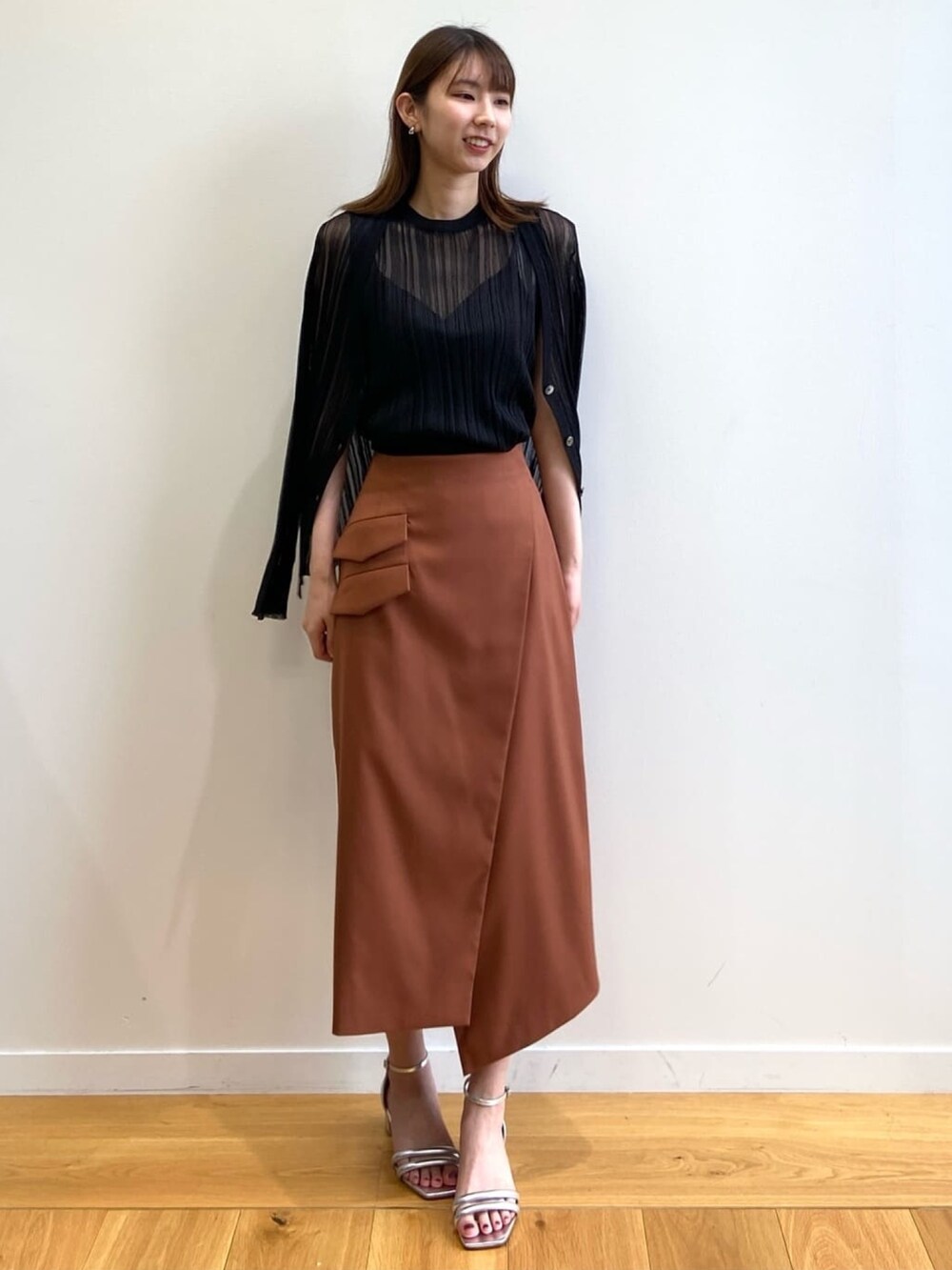 ブラウン系のスカート、シルバー系のサンダル、ブラック系のニット/セーターを着用したレディースの春コーディネートの2枚目の写真