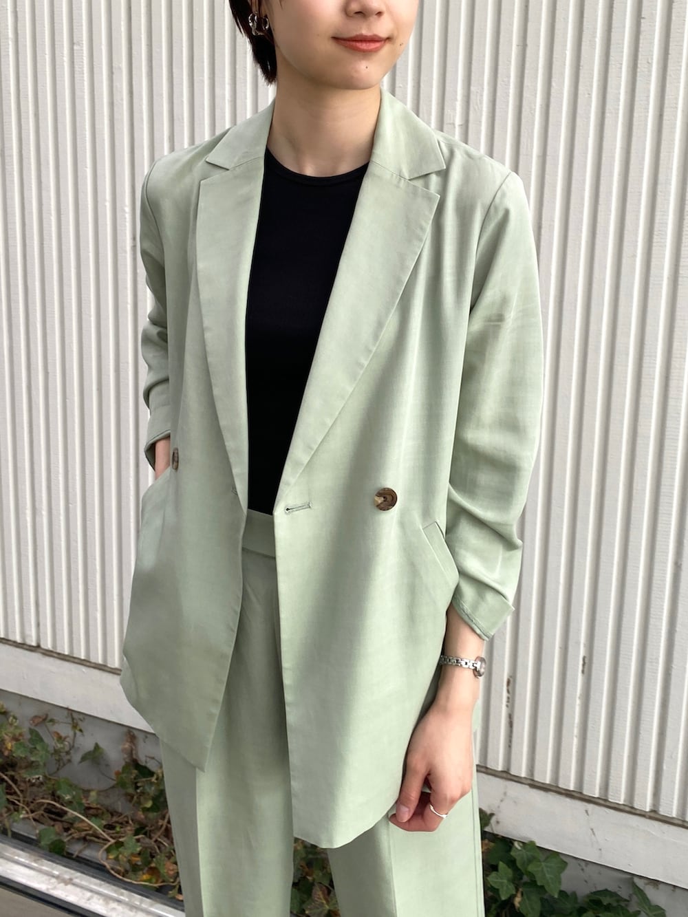 グリーン系のテーラードジャケット、ブラック系のタンクトップ、グリーン系のその他パンツを着用したレディースの春コーディネートの2枚目の写真