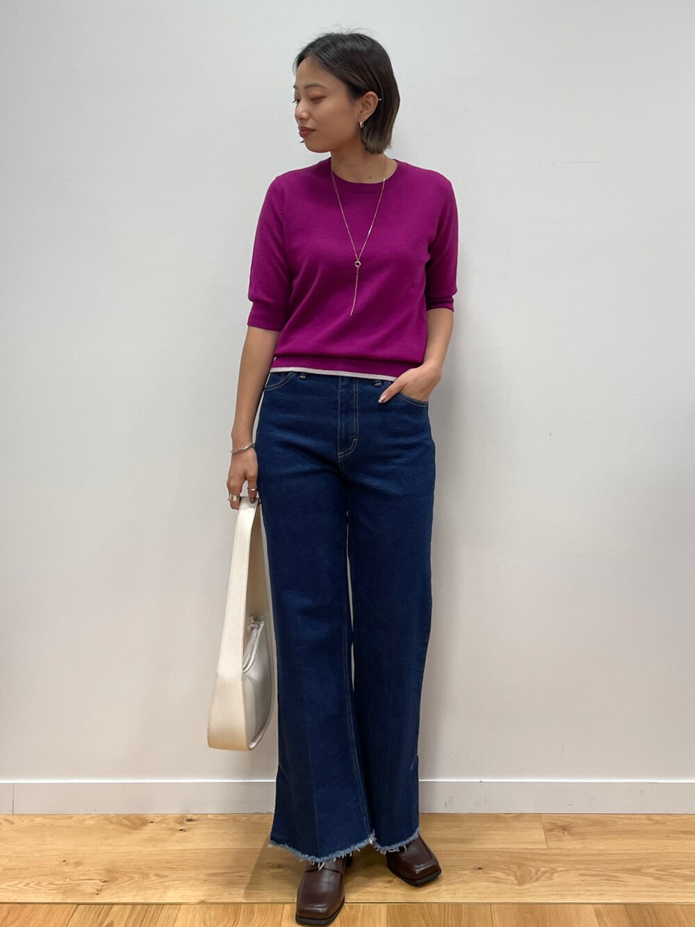 ブラウン系のノーカラーコート、レッド系のニット/セーター、ブルー系のその他パンツを着用したレディースの秋コーディネートの3枚目の写真