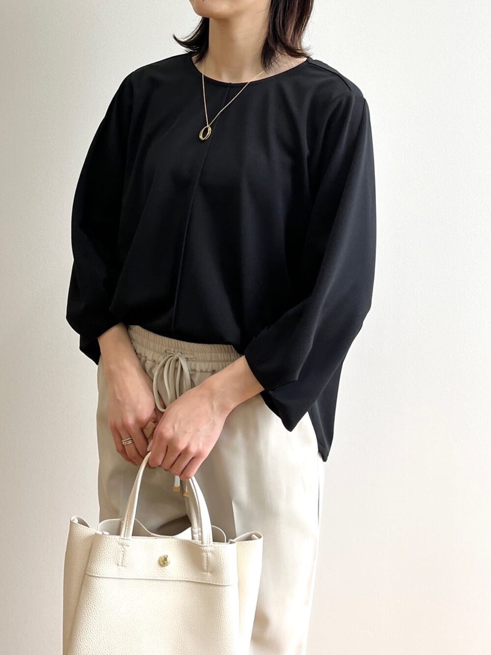 ブラック系のTシャツ/カットソー、ベージュ系のその他パンツ、ブラック系のサンダルを着用したレディースの春コーディネートの4枚目の写真