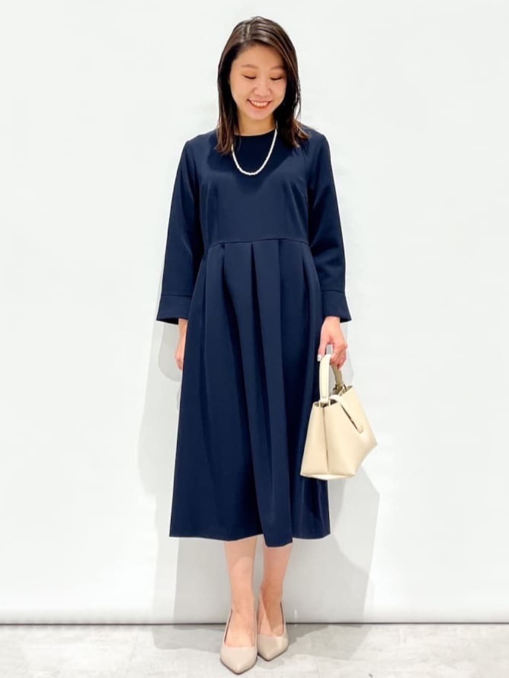 ブルー系のワンピース、ブラック系のショルダーバッグ、ブラック系のパンプスを着用したレディースの冬コーディネートの4枚目の写真