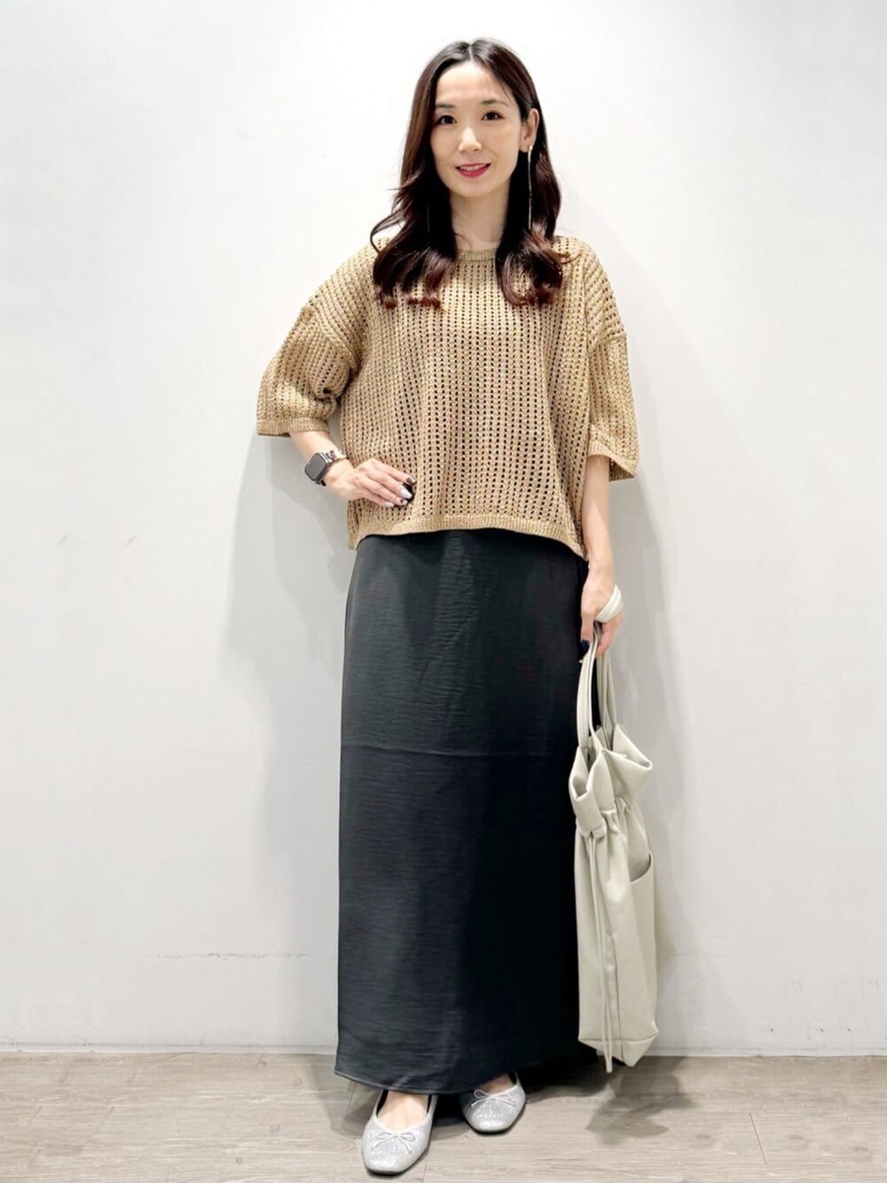 ゴールド系のニット/セーター、グレー系のトートバッグ、グレー系のスカートを着用したレディースの秋コーディネートの2枚目の写真