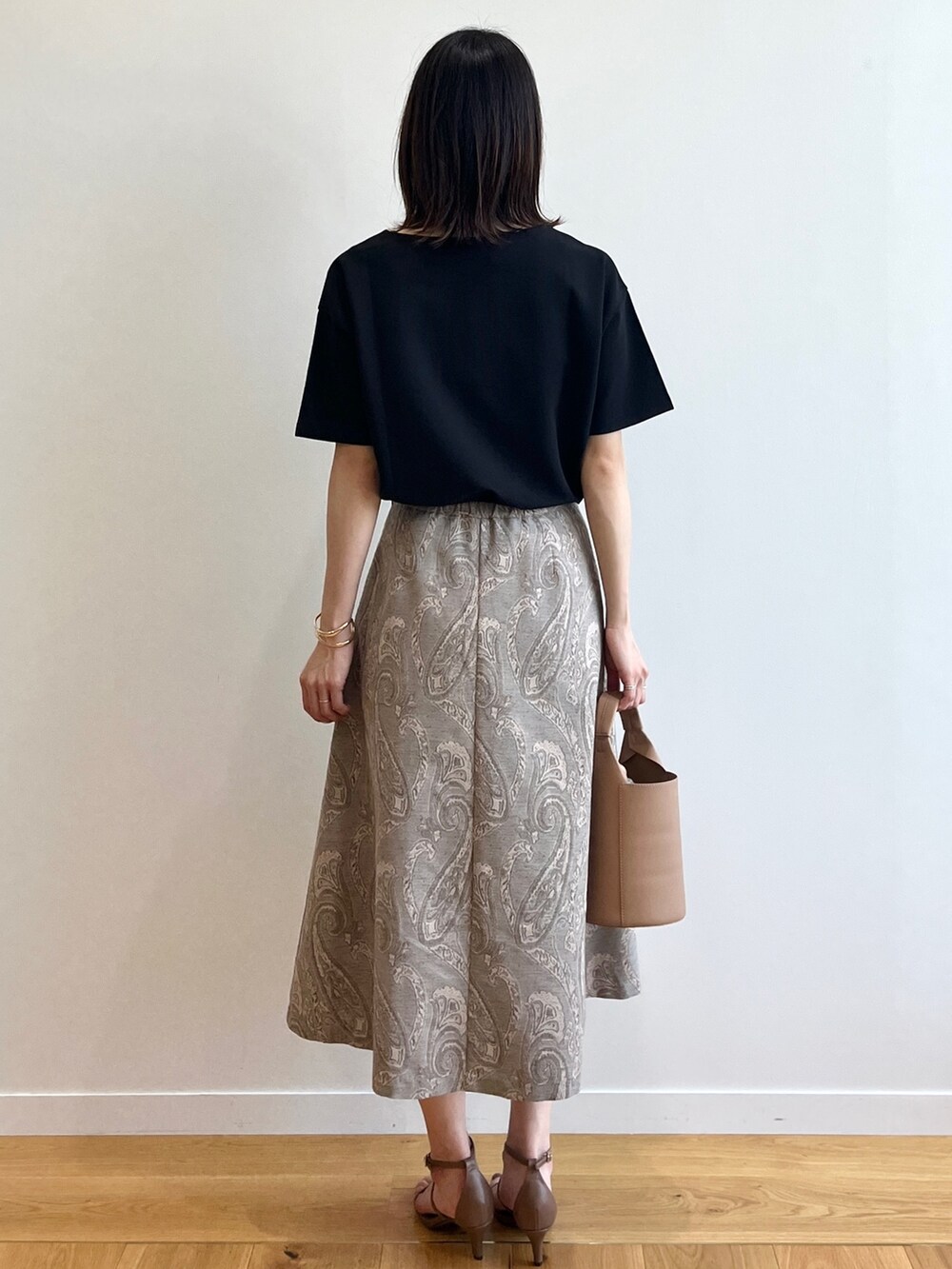 ブラウン系のサンダル、ベージュ系のスカート、イエロー系のトートバッグを着用したレディースの夏コーディネートの2枚目の写真