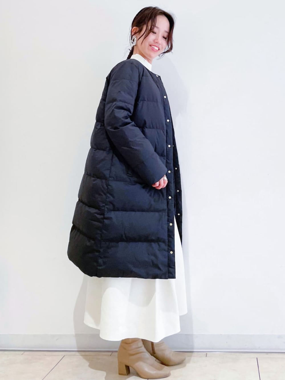 ブラック系のダウンジャケット/コート、ホワイト系のニット/セーター、ベージュ系のブーツを着用したレディースの冬コーディネートの3枚目の写真