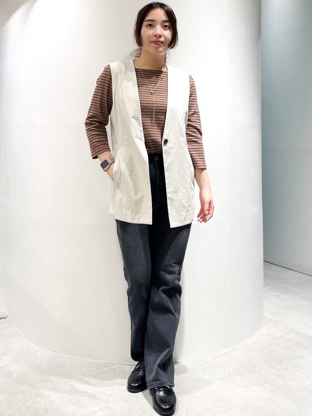 ブラック系のドレスシューズ、ブラック系のデニムパンツ、ホワイト系のベストを着用したレディースの夏コーディネートの3枚目の写真