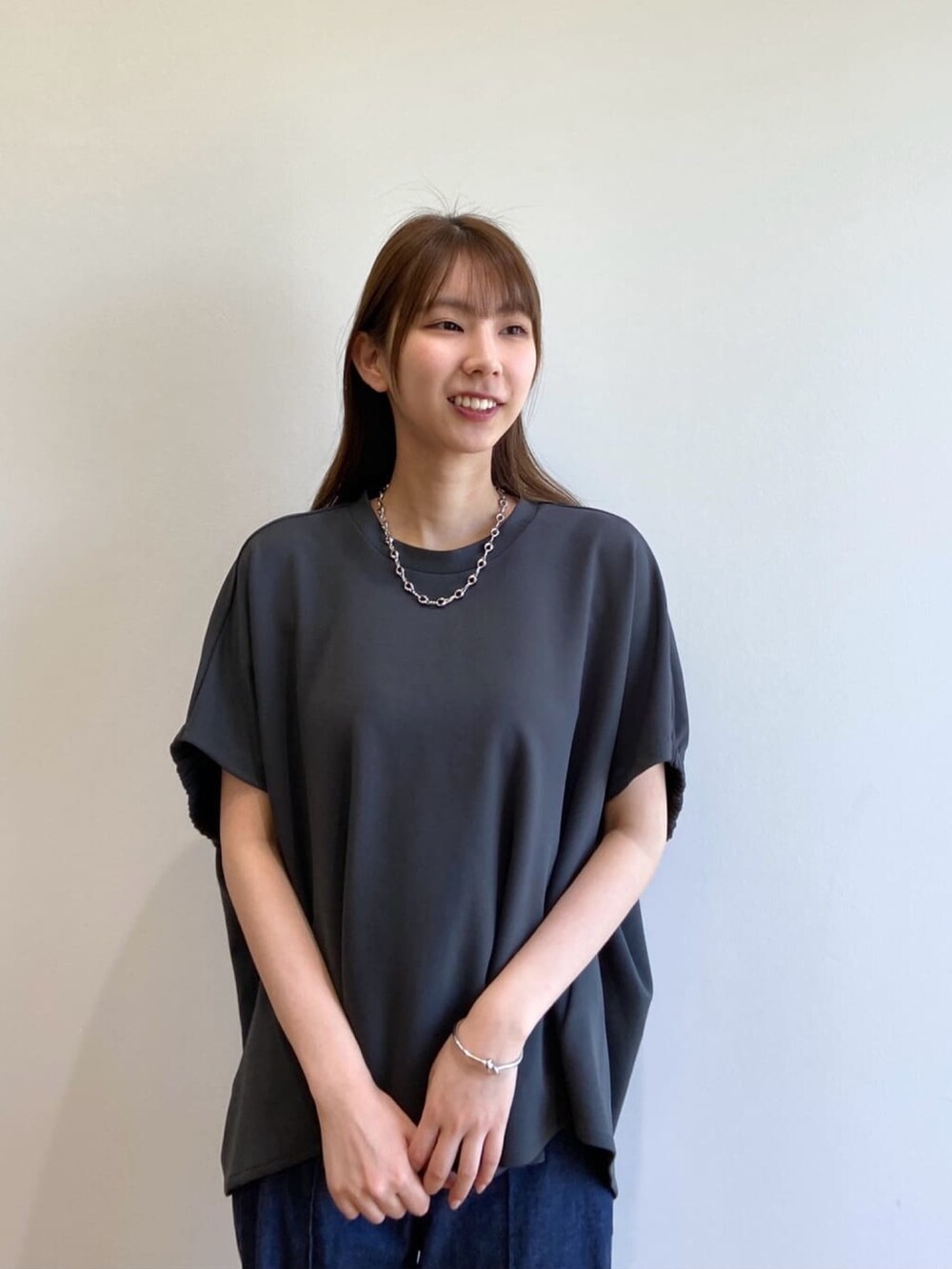 グレー系のTシャツ/カットソー、ブルー系のデニムパンツ、ブラック系のサンダルを着用したレディースの春コーディネートの6枚目の写真