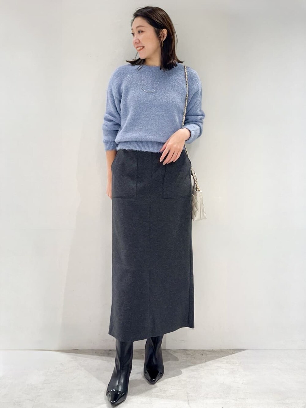 ブラック系のダウンジャケット/コート、グレー系のスカート、ブラック系のブーツを着用したレディースの秋コーディネートの5枚目の写真