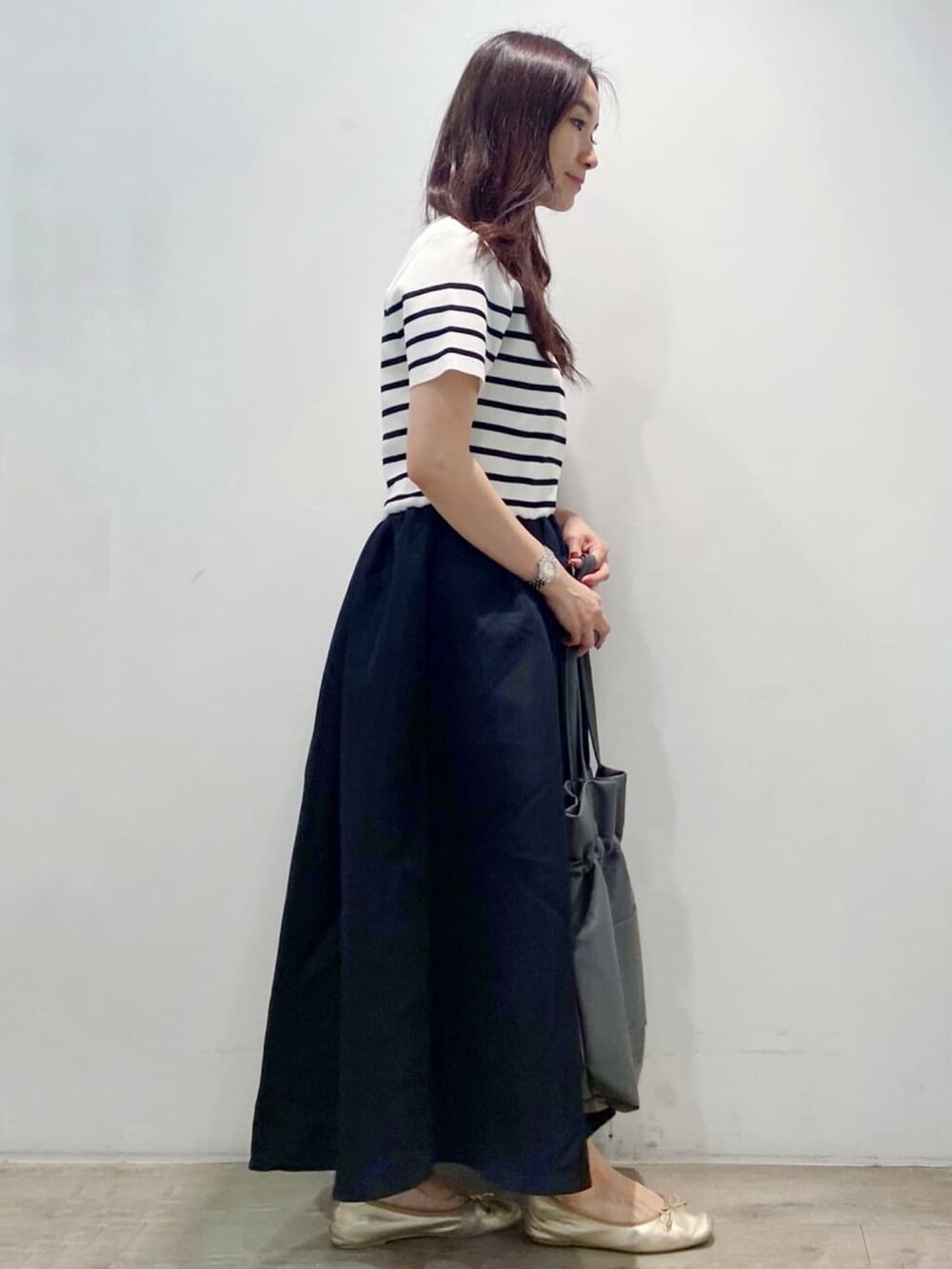 グレー系のトートバッグ、ブラック系のワンピース、ゴールド系のその他シューズを着用したレディースの夏コーディネートの7枚目の写真