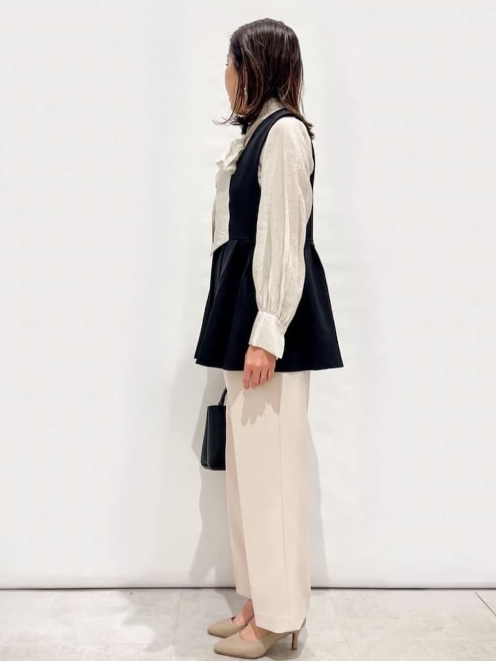 ホワイト系のシャツ/ブラウス、ブラック系のベスト、ベージュ系のその他パンツを着用したレディースの春コーディネートの2枚目の写真