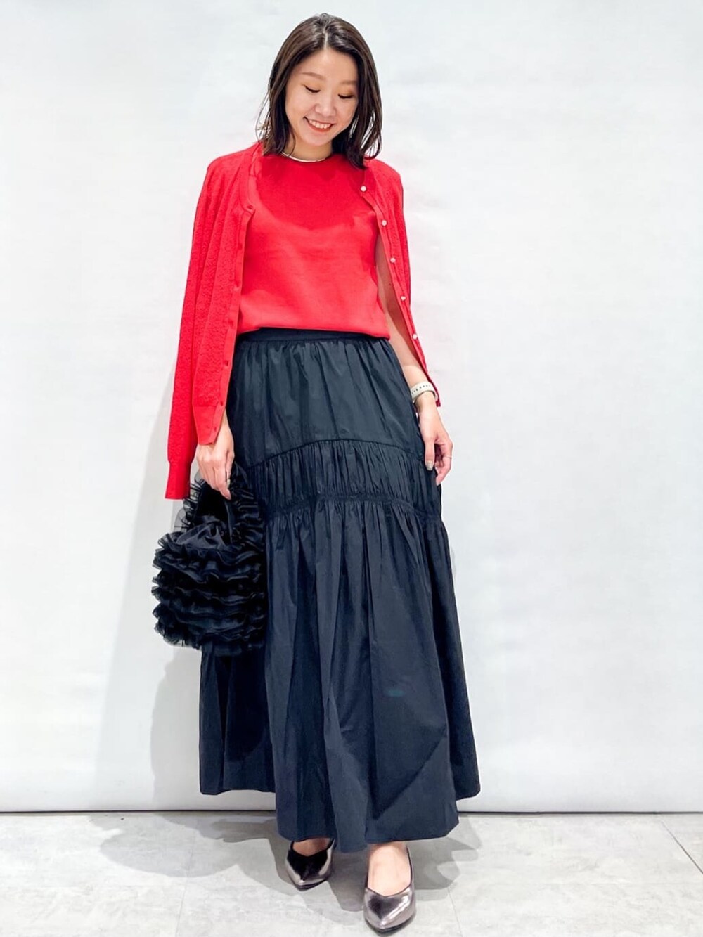 レッド系のカーディガン/ボレロ、レッド系のニット/セーター、ブラック系のスカートを着用したレディースの夏コーディネートの3枚目の写真