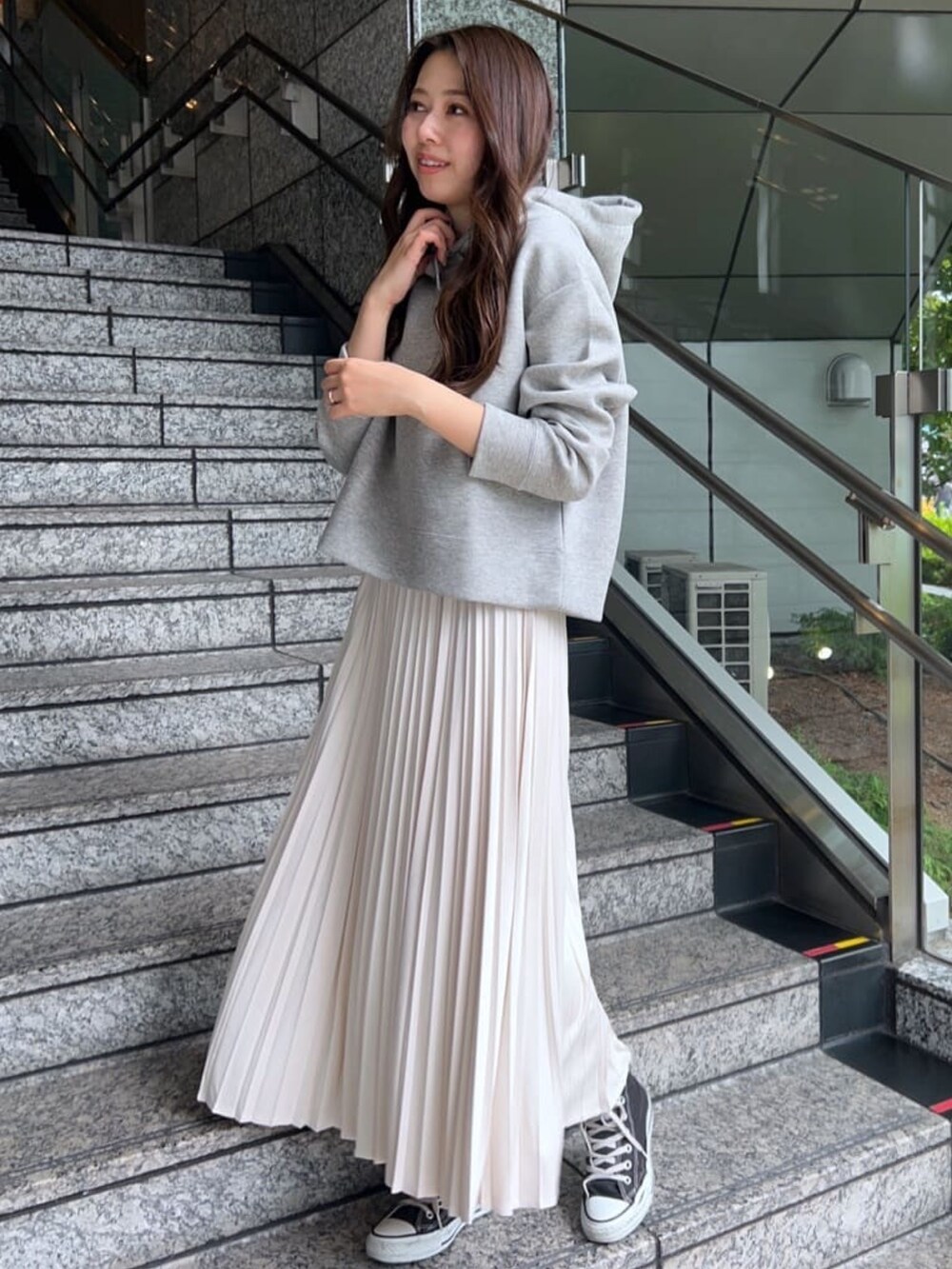 ホワイト系のスカート、グレー系のパーカーを着用したレディースの秋コーディネートの2枚目の写真