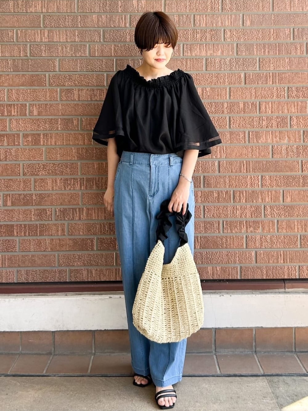 ブラック系のシャツ/ブラウス、ブラック系のサンダル、ベージュ系のショルダーバッグを着用したレディースの夏コーディネートの2枚目の写真