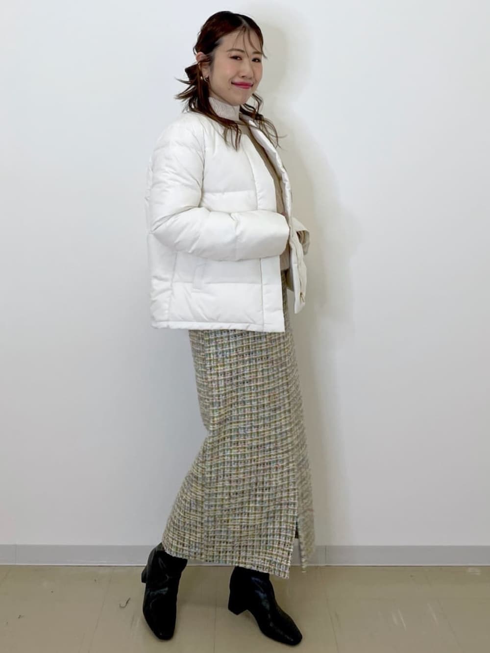 グリーン系のスカート、ホワイト系のダウンジャケット/コート、ホワイト系のニット/セーターを着用したレディースの冬コーディネートの3枚目の写真