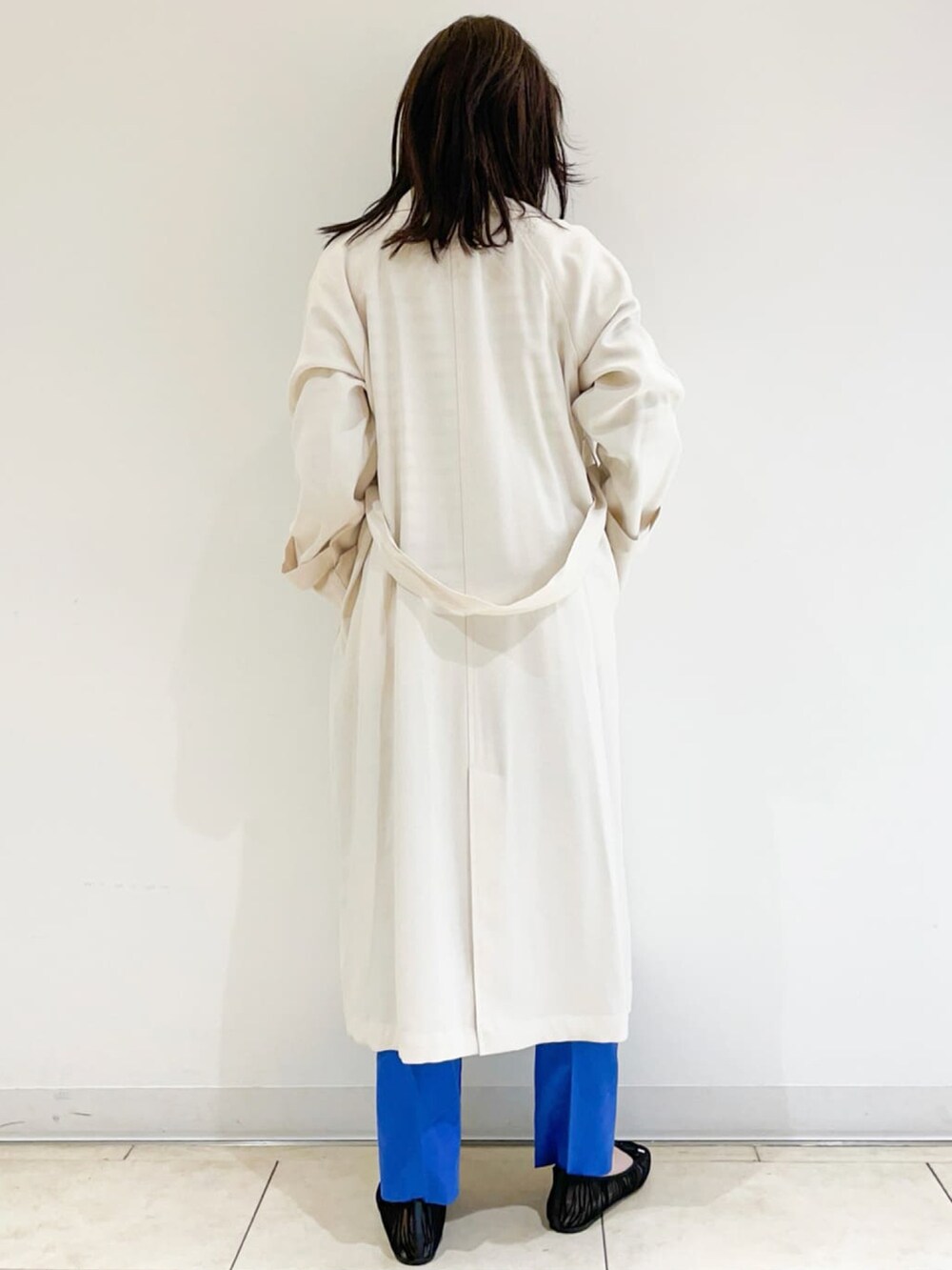 ホワイト系のトレンチコート、ホワイト系のニット/セーター、ブラック系のショルダーバッグを着用したレディースの春コーディネートの3枚目の写真