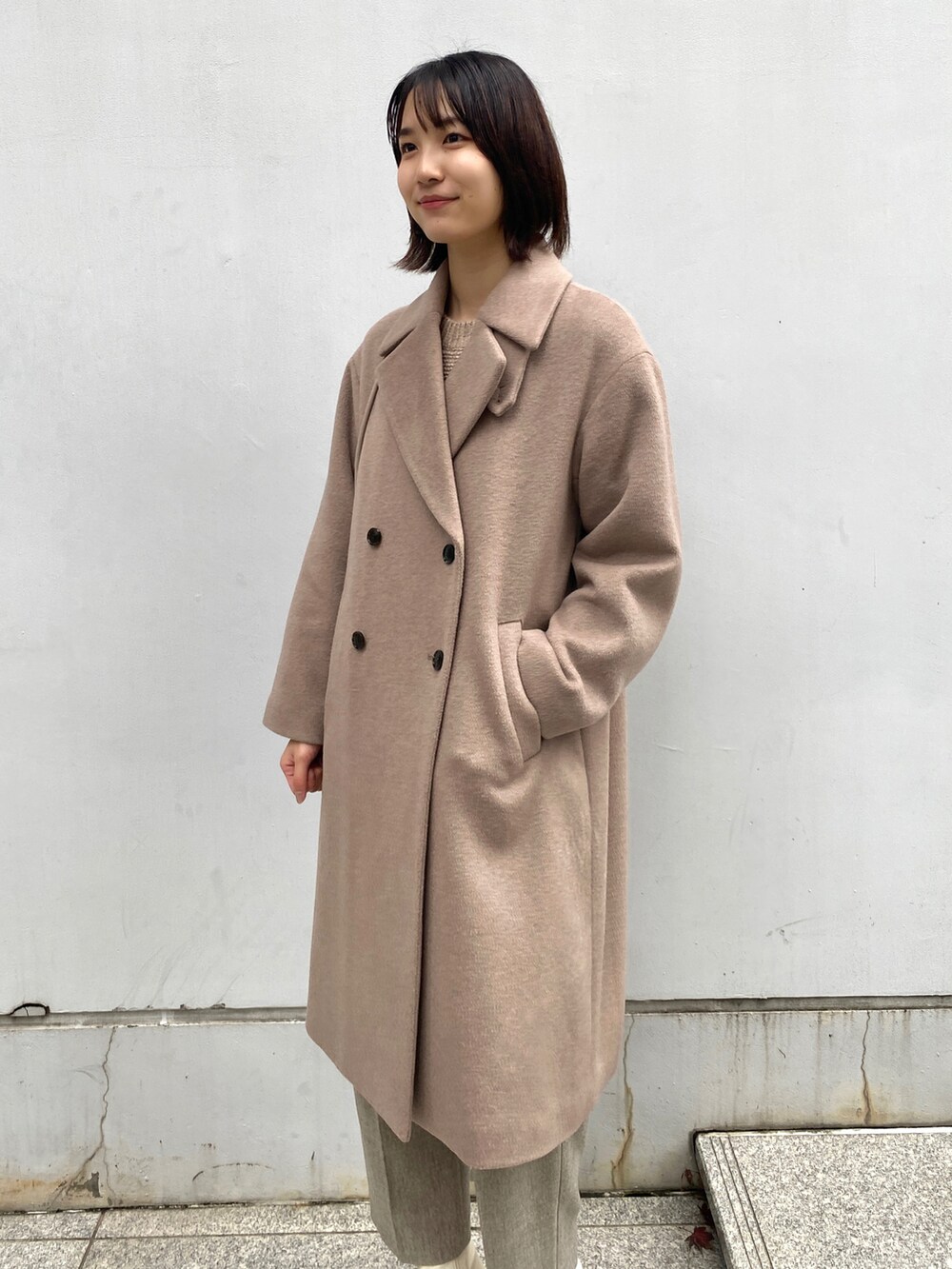 ベージュ系のチェスターコート、ベージュ系のその他パンツ、ホワイト系のブーツを着用したレディースの冬コーディネートの3枚目の写真