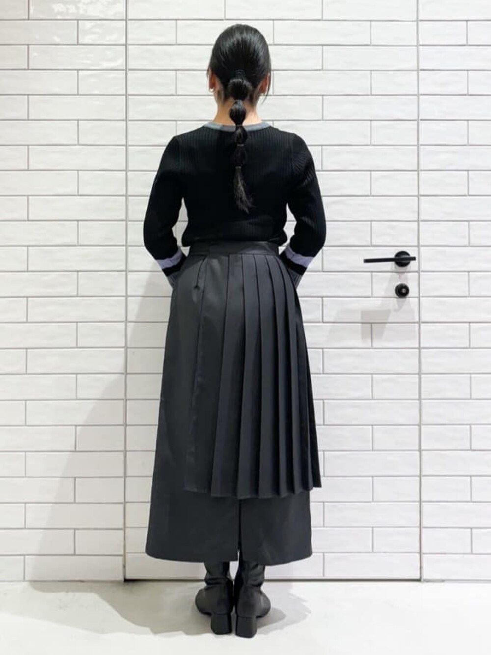 グレー系のニット/セーター、グレー系のスカート、ブラック系のトートバッグを着用したレディースの秋コーディネートの3枚目の写真