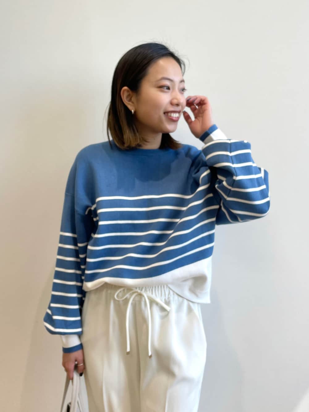 ホワイト系のノーカラーコート、ブルー系のニット/セーター、ホワイト系のその他パンツを着用したレディースの春コーディネートの4枚目の写真