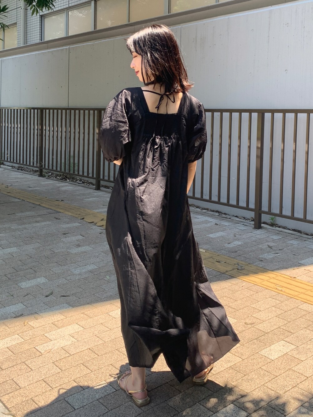 ブラック系のワンピース、ホワイト系のショルダーバッグ、ゴールド系のサンダルを着用したレディースの夏コーディネートの2枚目の写真